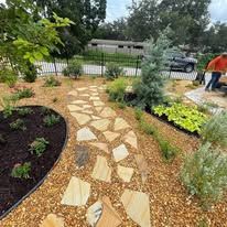 A man is working in a garden with a stone walkway.