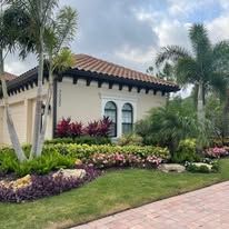 A house with a tile roof and a lot of plants in front of it.