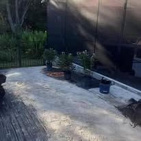 A patio with potted plants and a fence in the background.