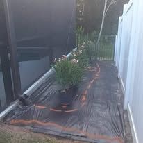 A patio with potted plants and a fence covered in plastic.