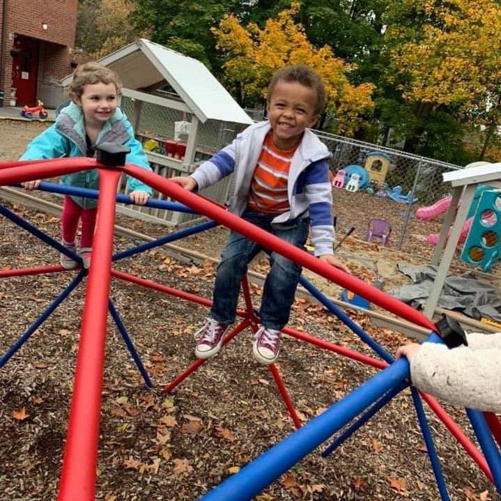 A boy and a girl are playing on a climbing frame