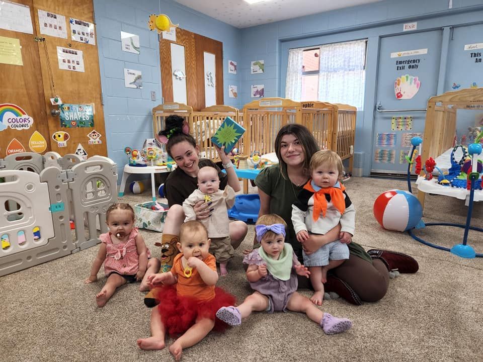 A group of babies are sitting on the floor in a classroom.