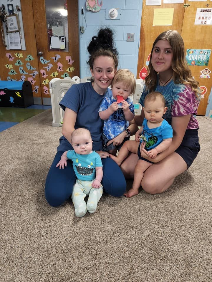 Two women are sitting on the floor with two babies.