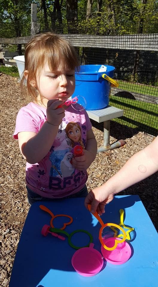 A little girl is sitting at a table playing with toys.