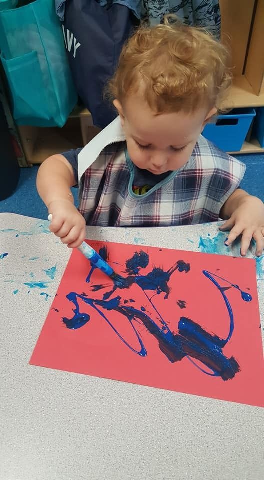 A little boy is sitting at a table painting with a marker.