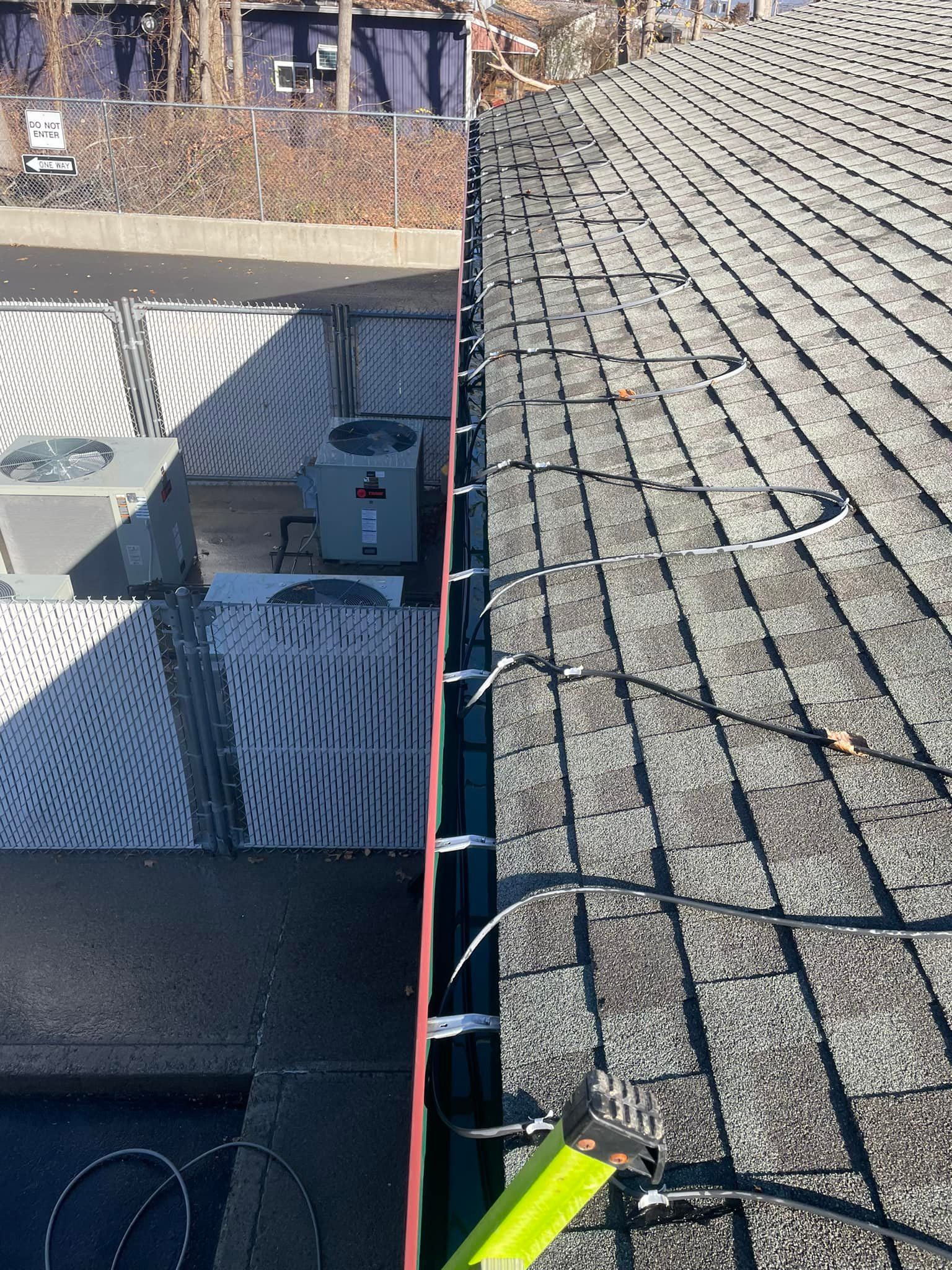 A person is measuring a gutter on a roof with a tape measure.