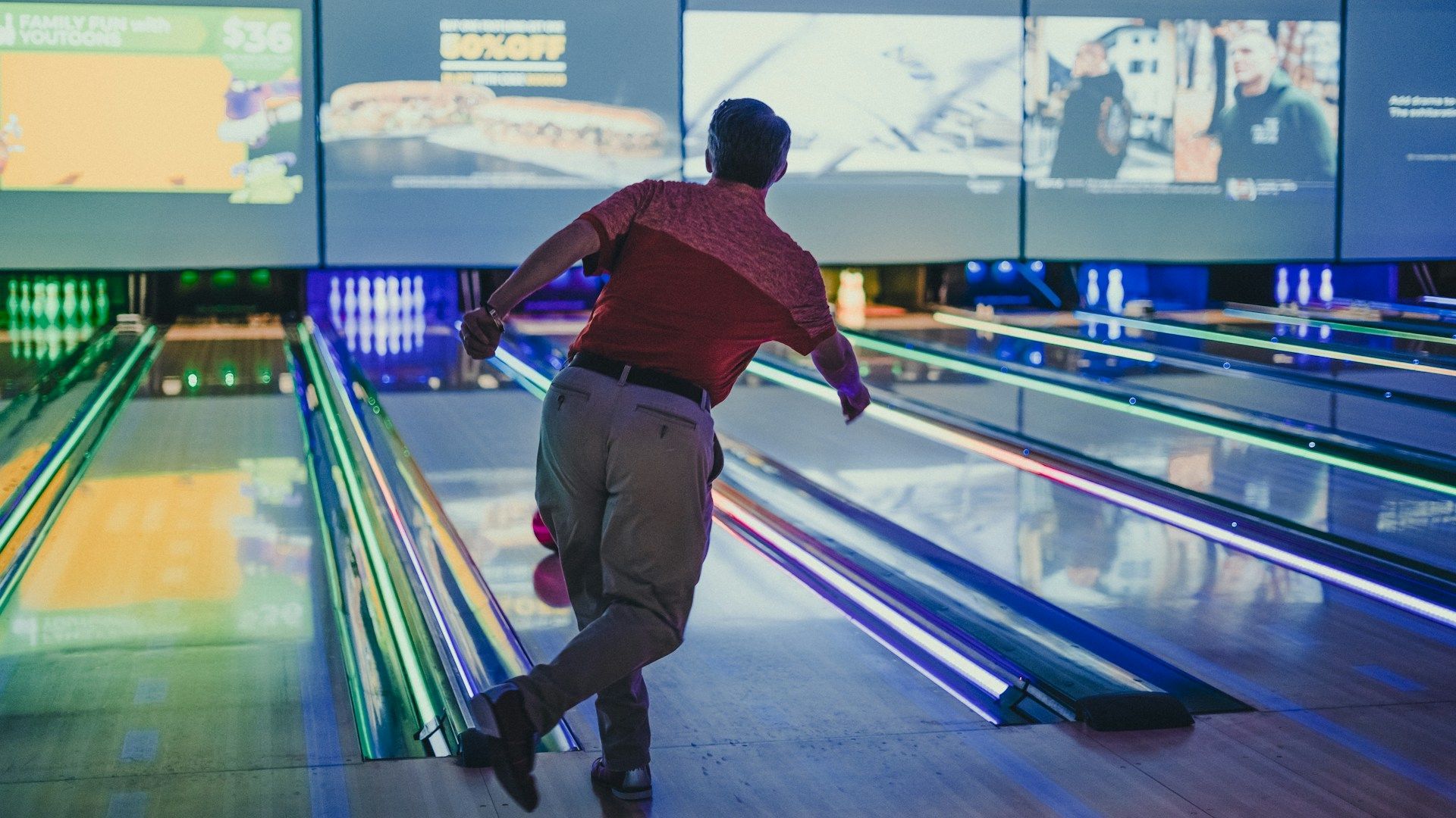 A man is throwing a bowling ball on a bowling alley.