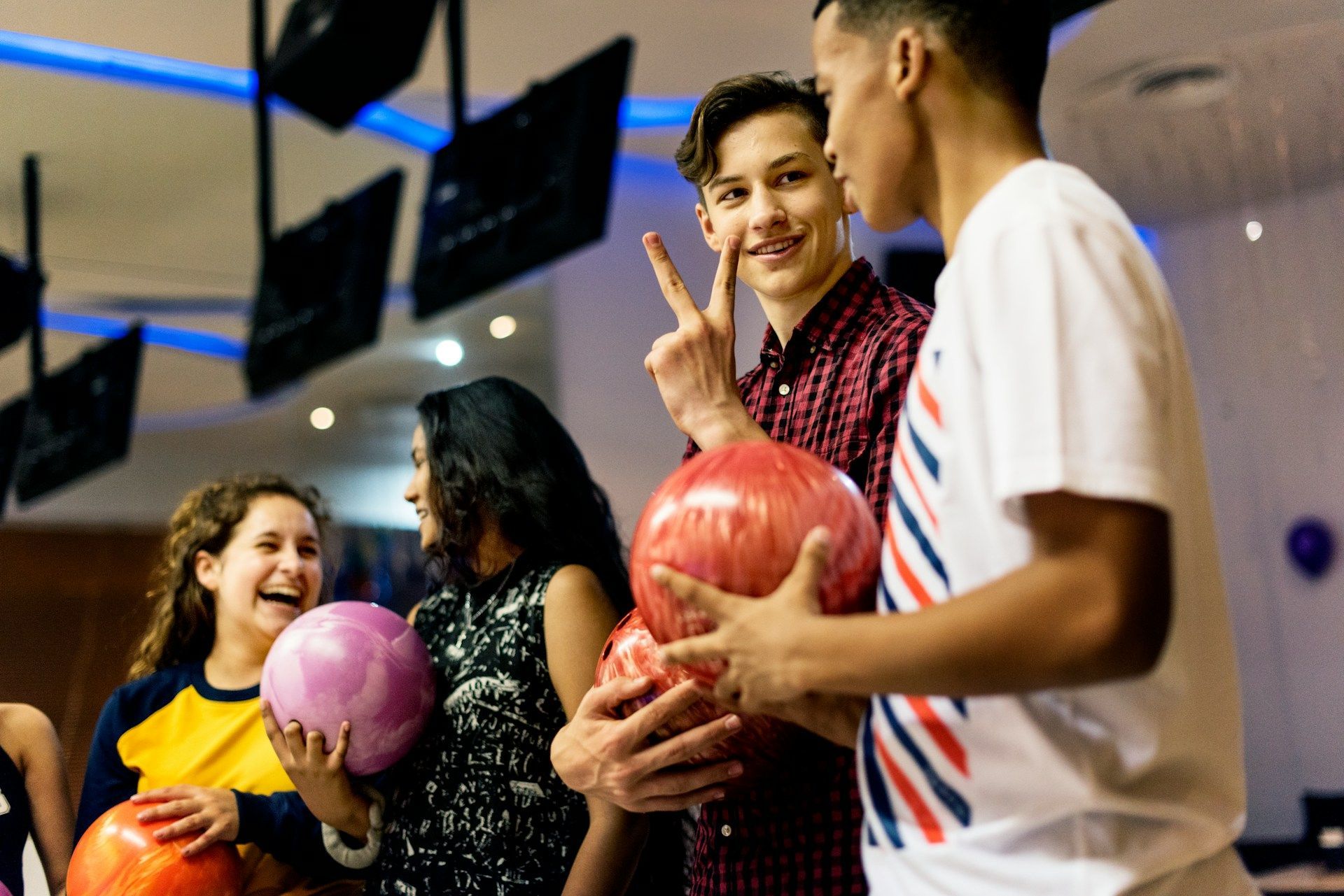 A group of young people are holding bowling balls in a bowling alley.
