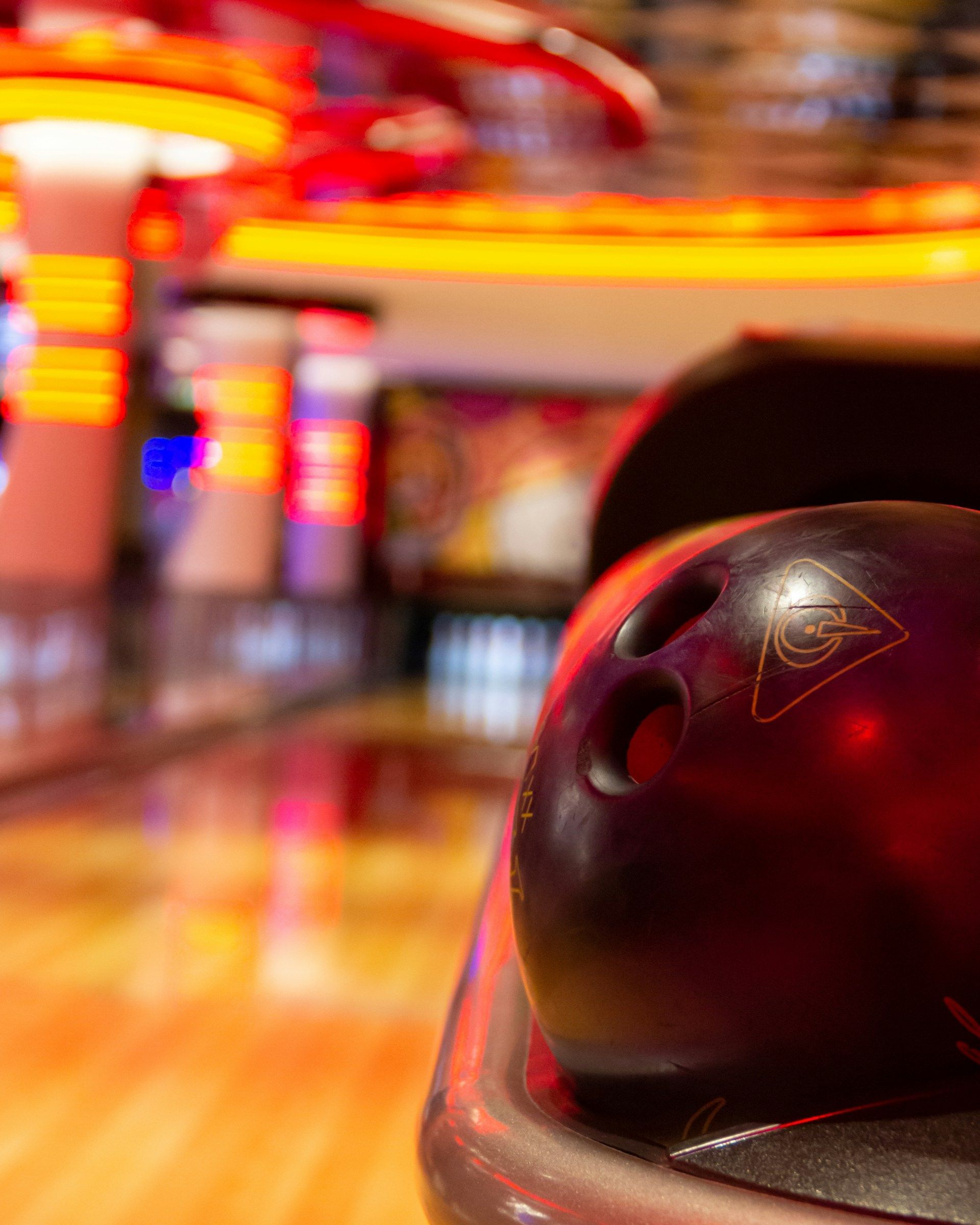 A bowling ball is sitting on a table in a bowling alley.