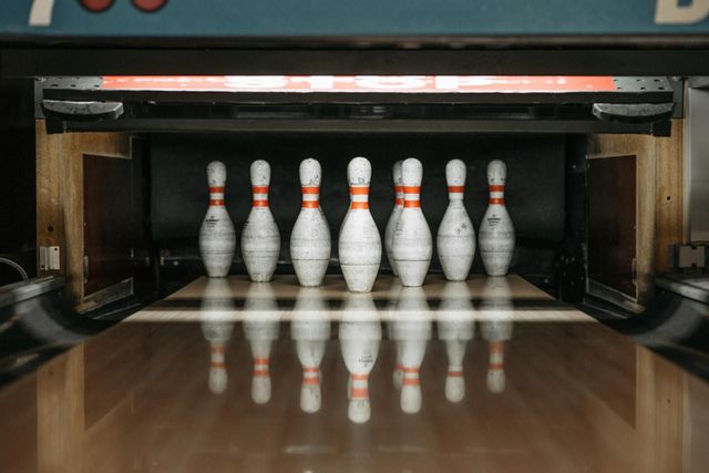 A row of bowling pins are lined up on a bowling alley.