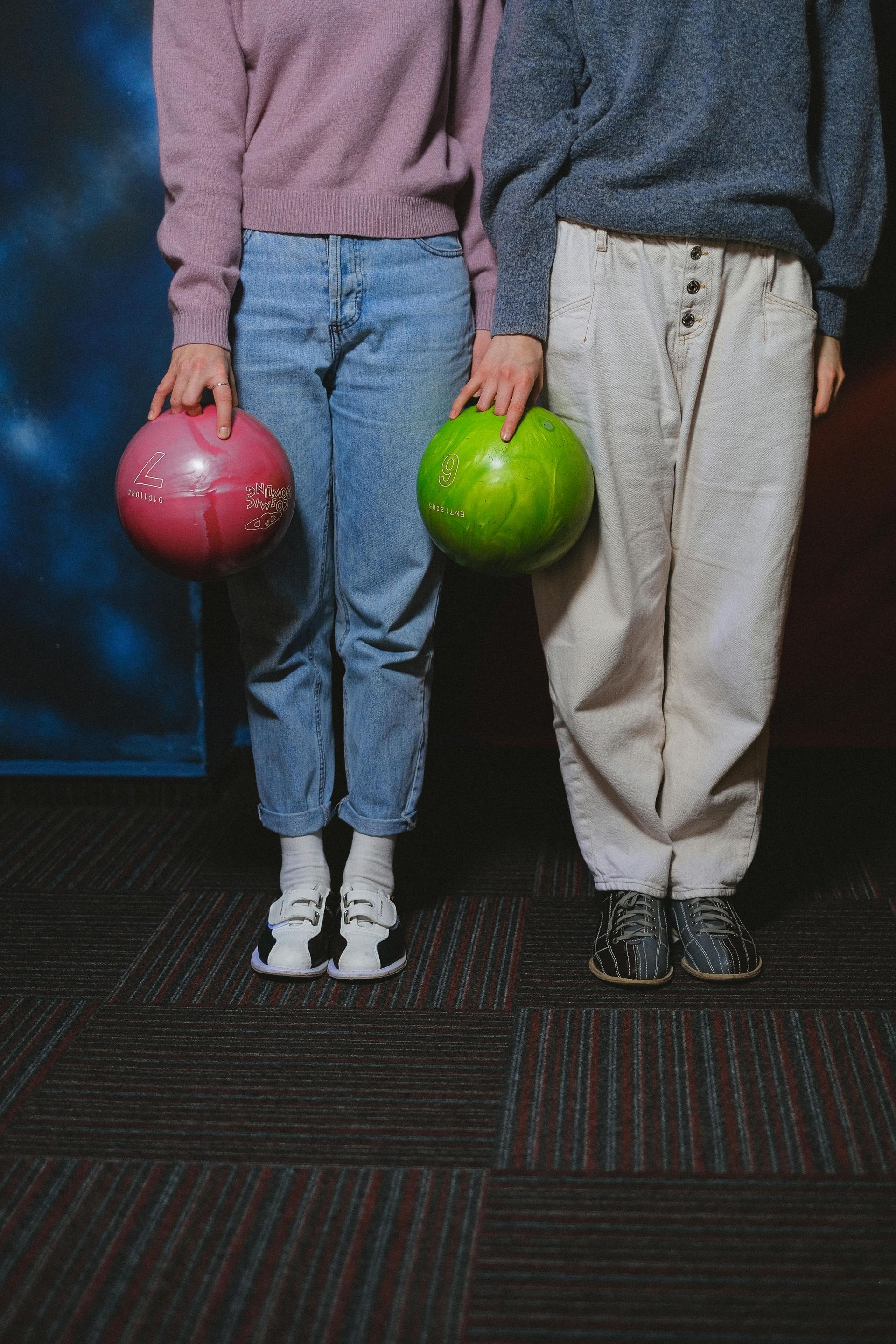A man and a woman are standing next to each other holding bowling balls.