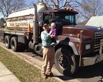Mr. Brogan holding granddaughter beside 2nd truck