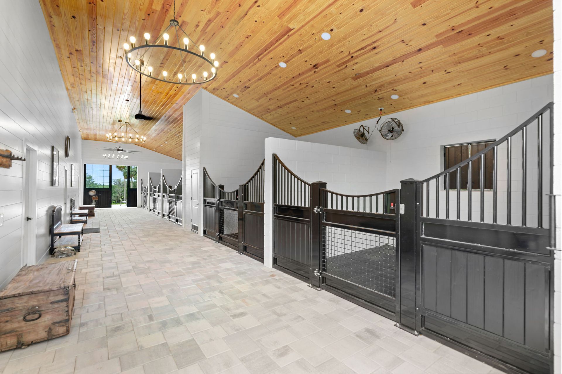 A horse stable with a wooden ceiling and a chandelier hanging from the ceiling.