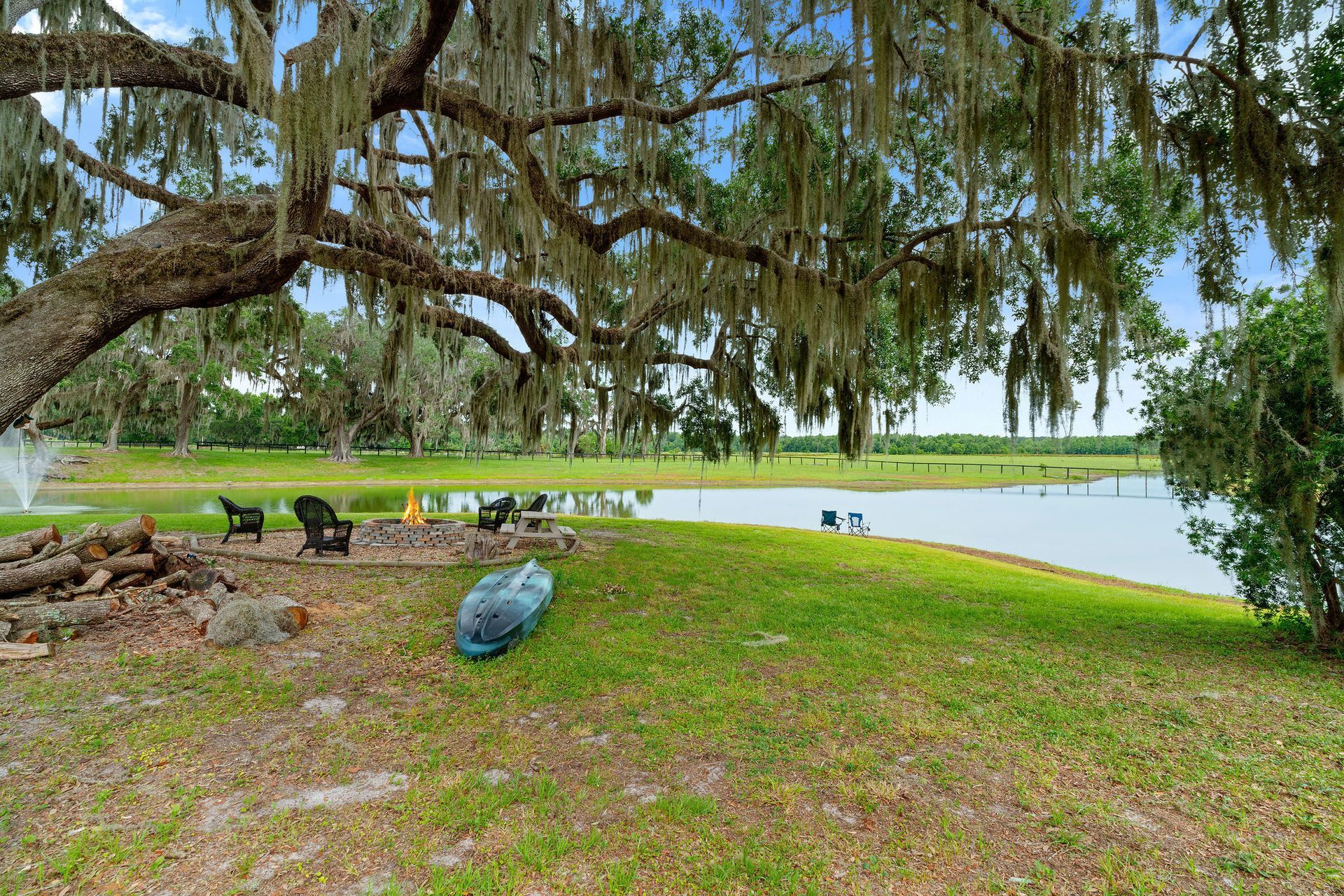 A kayak is sitting under a tree next to a lake.