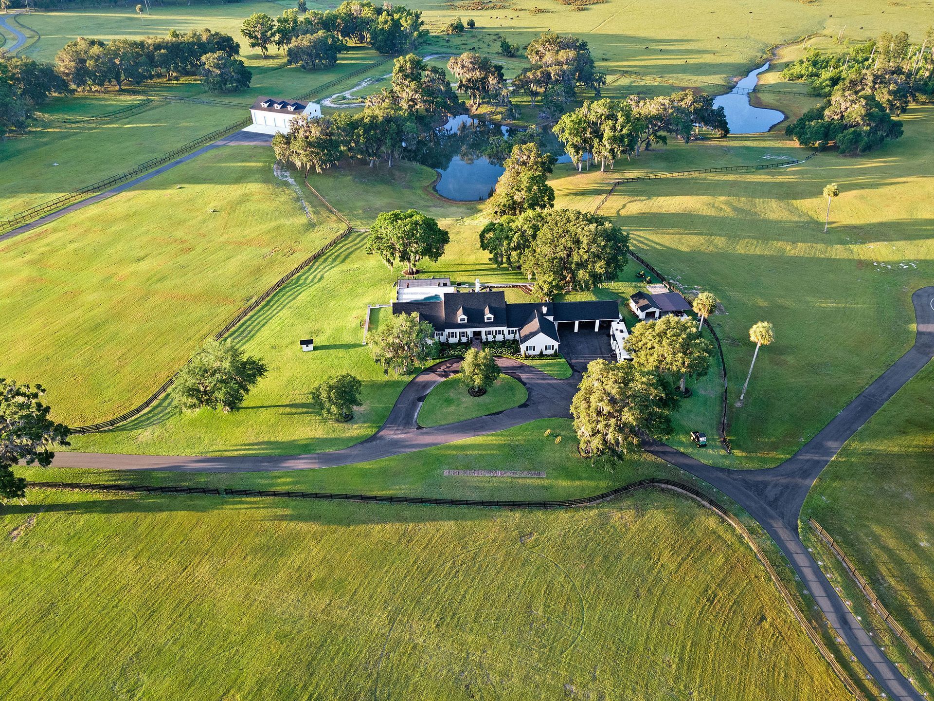 An aerial view of a house in the middle of a grassy field