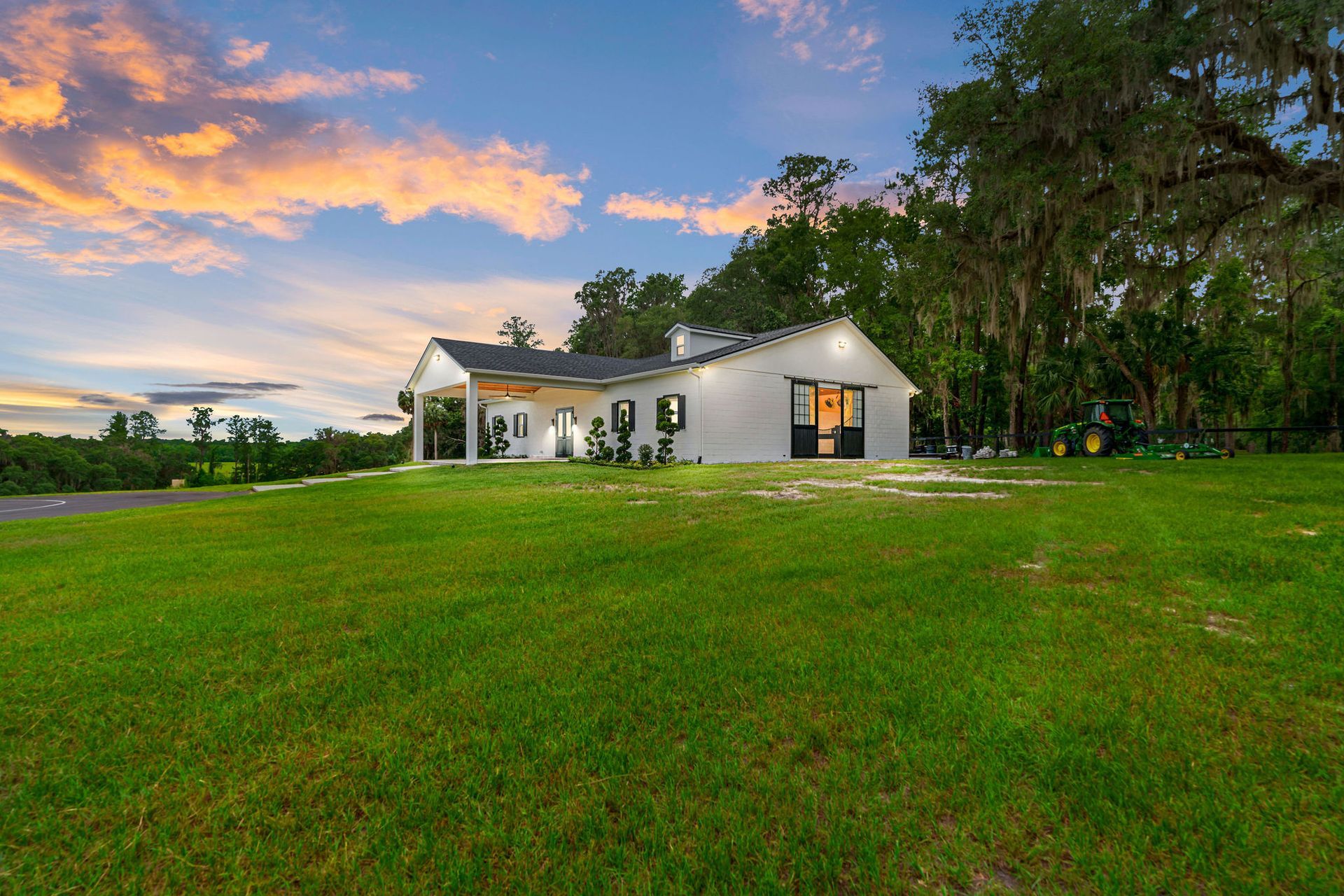 A white house is sitting on top of a lush green field.