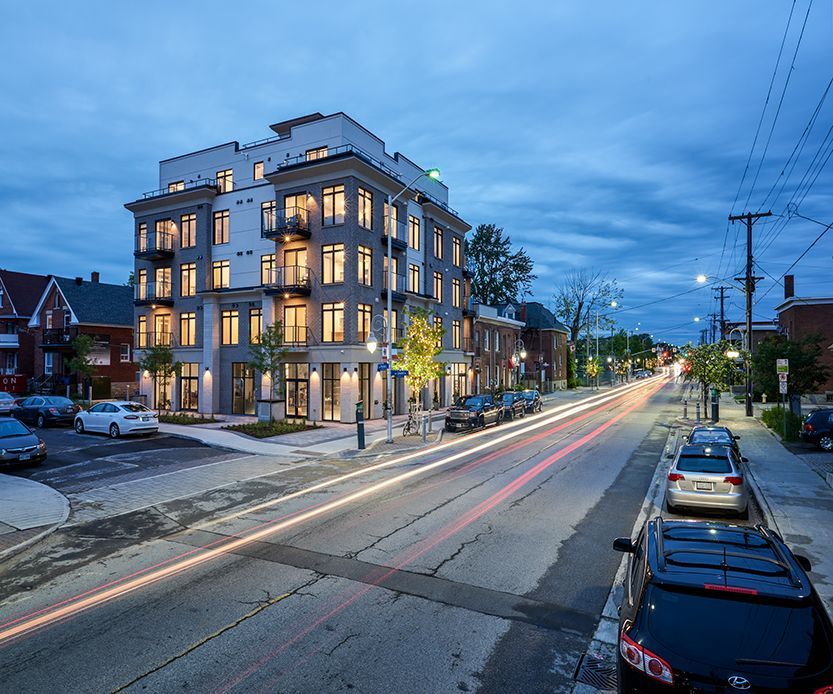 A row of cars are parked on the side of the road in front of a building.