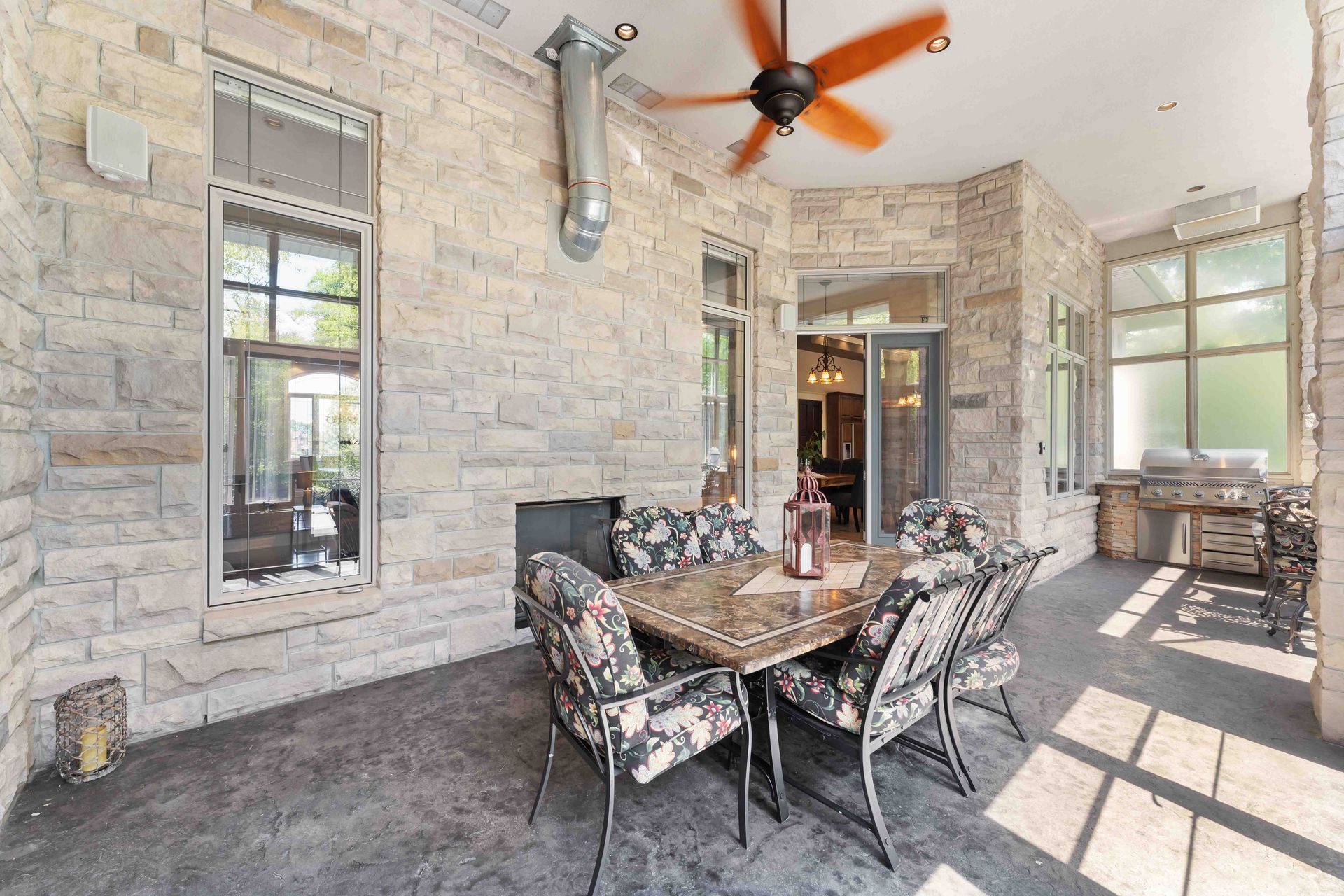 A patio with a table and chairs and a ceiling fan.