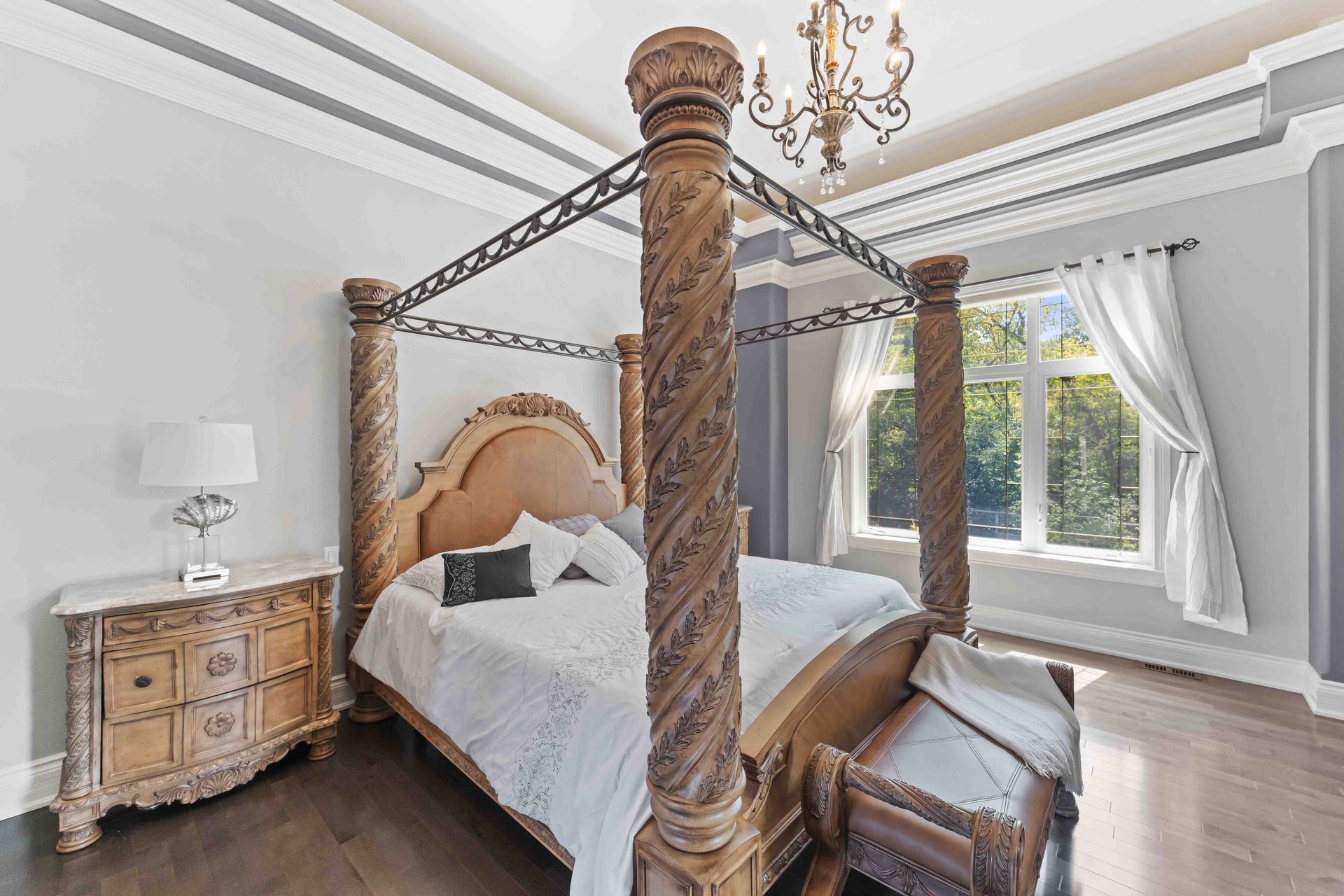 A bedroom with a canopy bed and a chandelier.