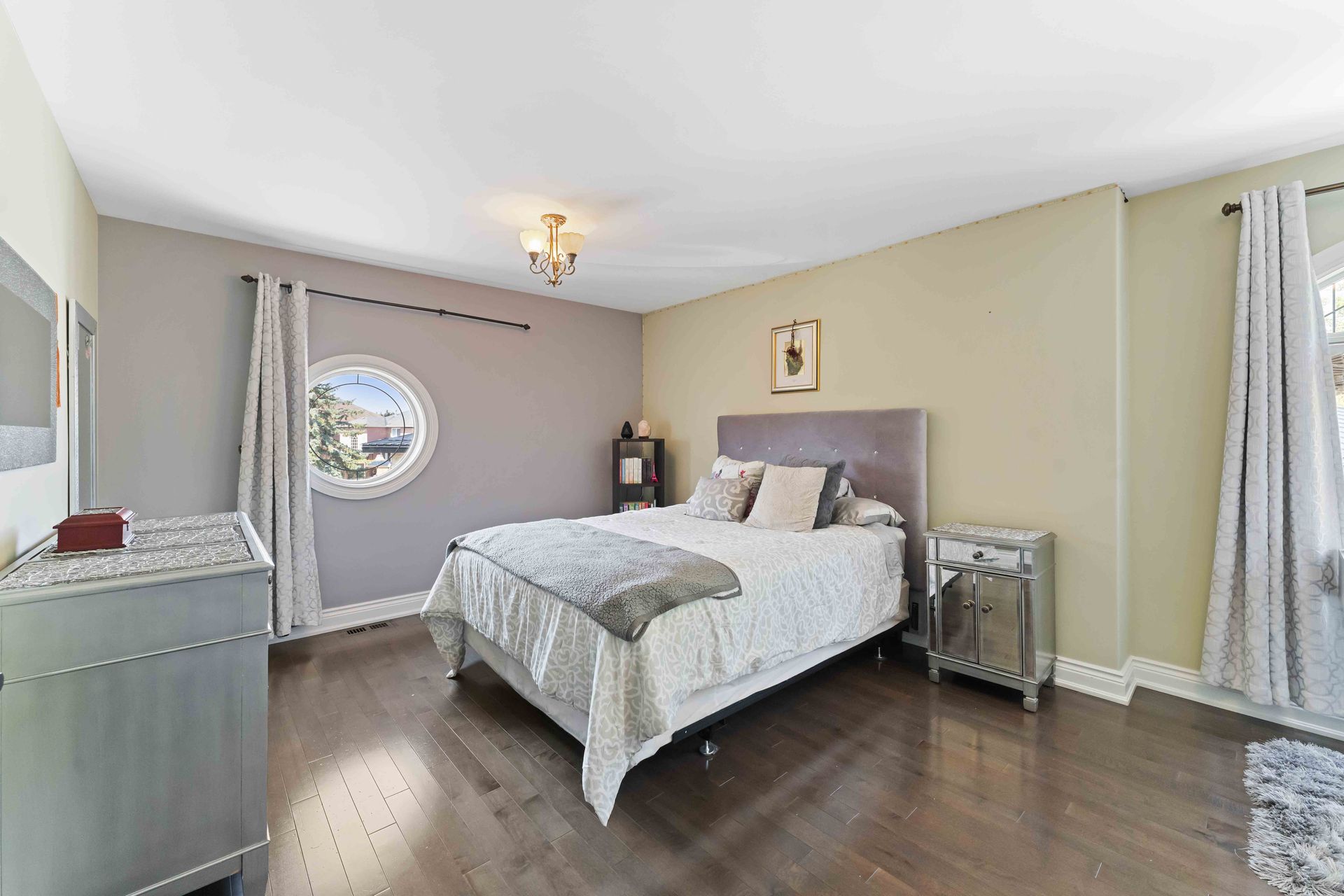 A bedroom with a bed , dresser , nightstand and window.