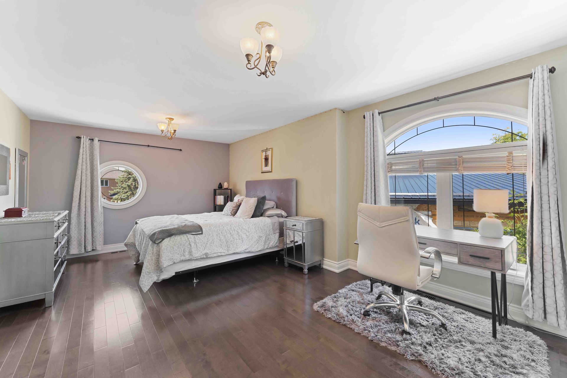 A bedroom with a large bed , desk , chair and window.