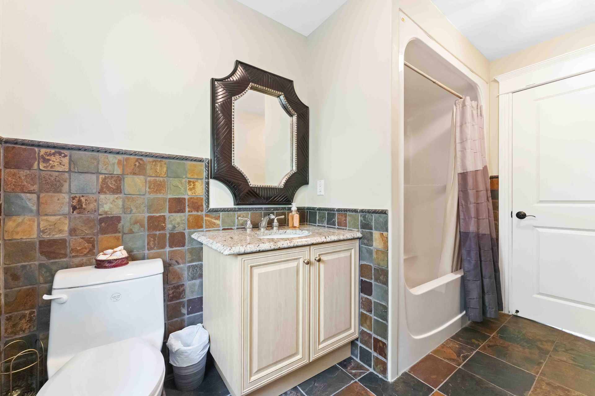 A bathroom with a toilet , sink , mirror and shower.