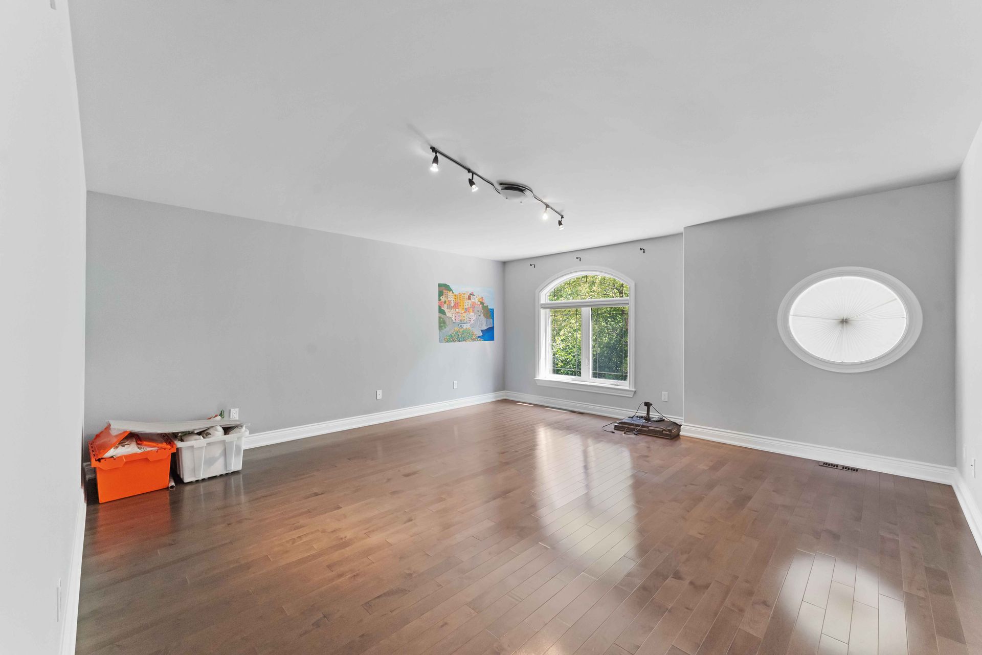 A large empty room with hardwood floors and a window.