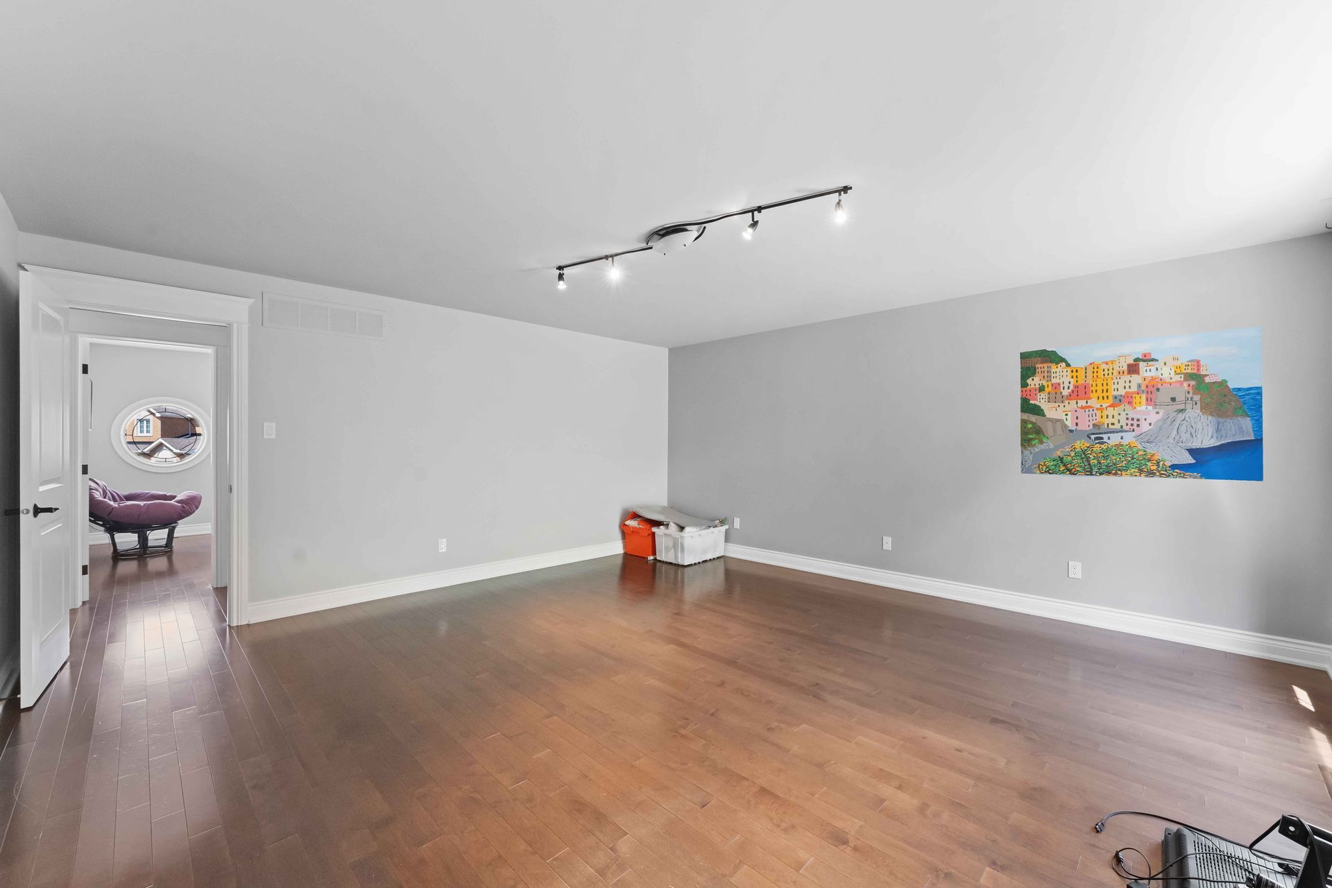 A living room with hardwood floors and a painting on the wall.