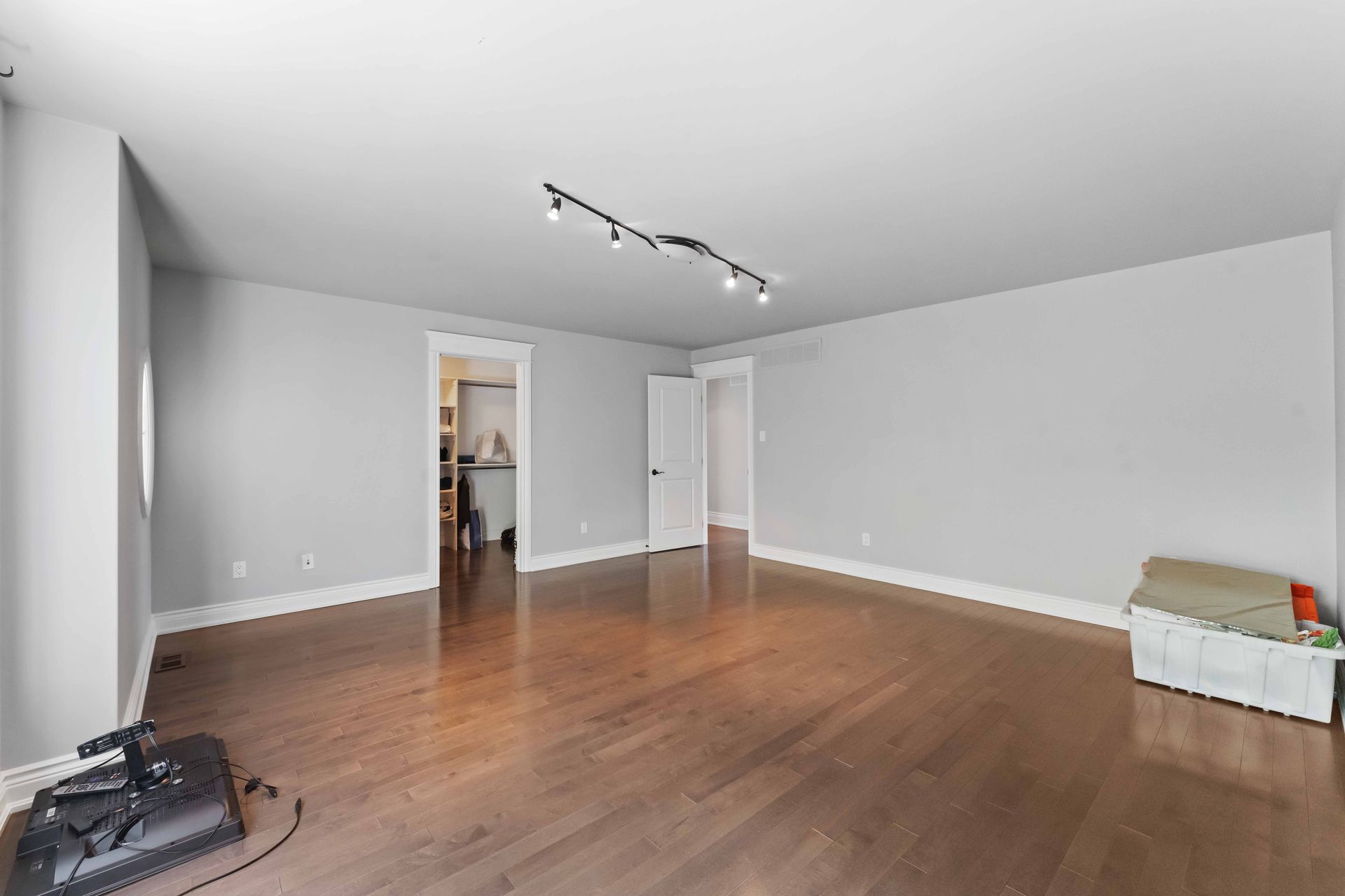 An empty living room with hardwood floors and white walls.