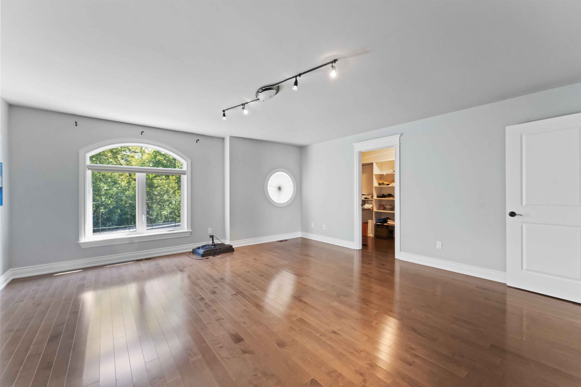 An empty living room with hardwood floors and white walls.