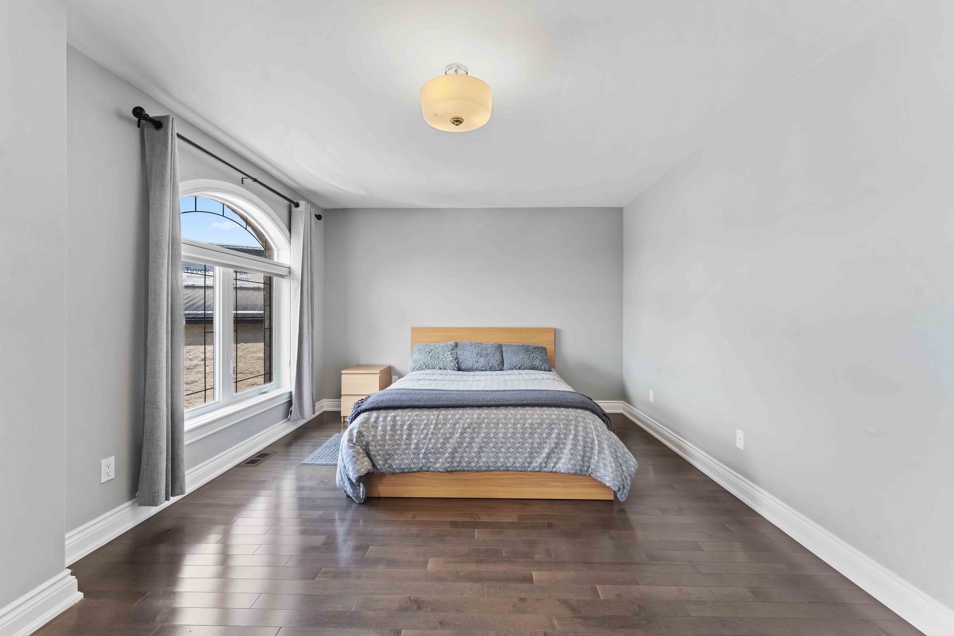 A bedroom with a bed , nightstand , and window.
