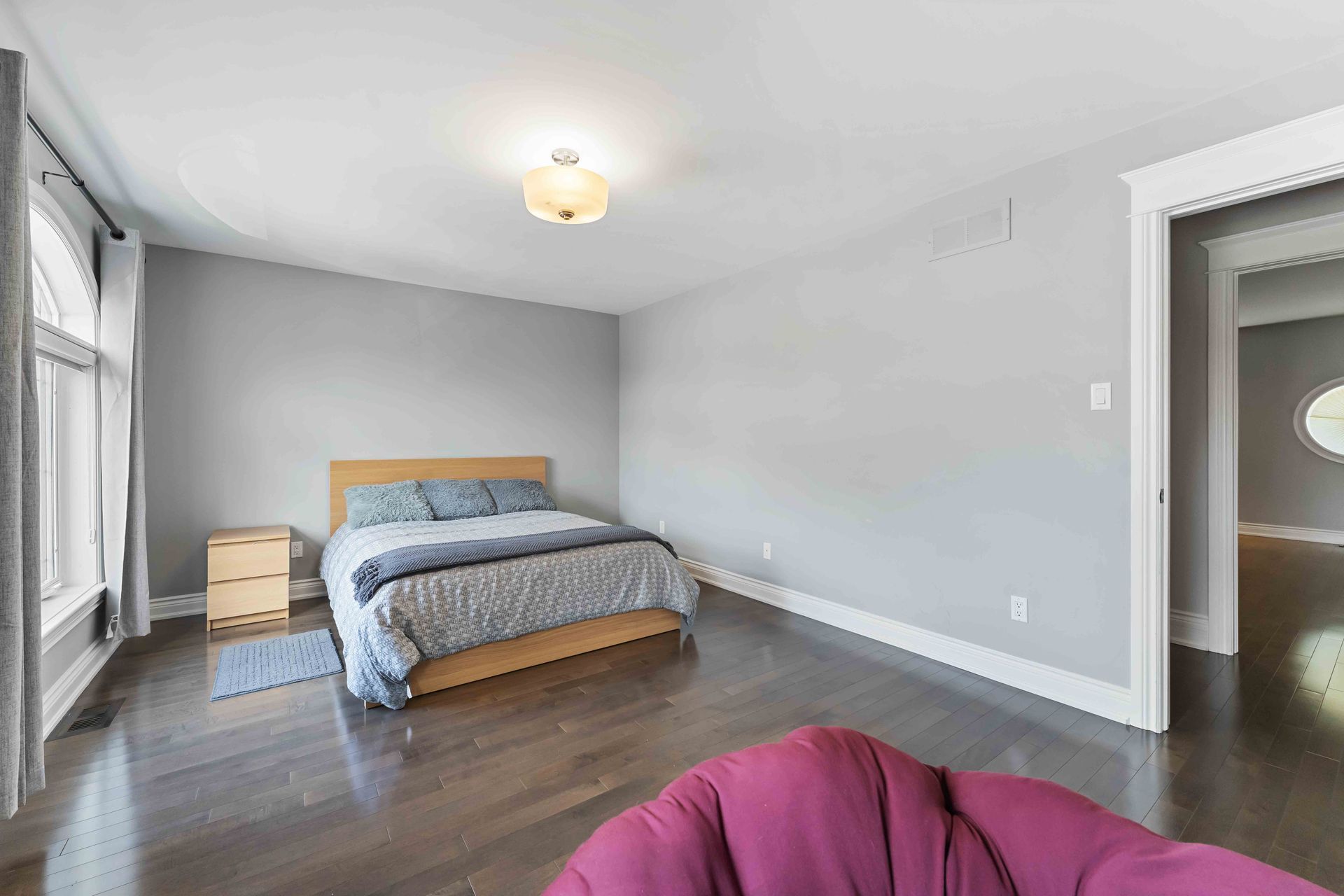 A bedroom with a bed , nightstand , chair and window.