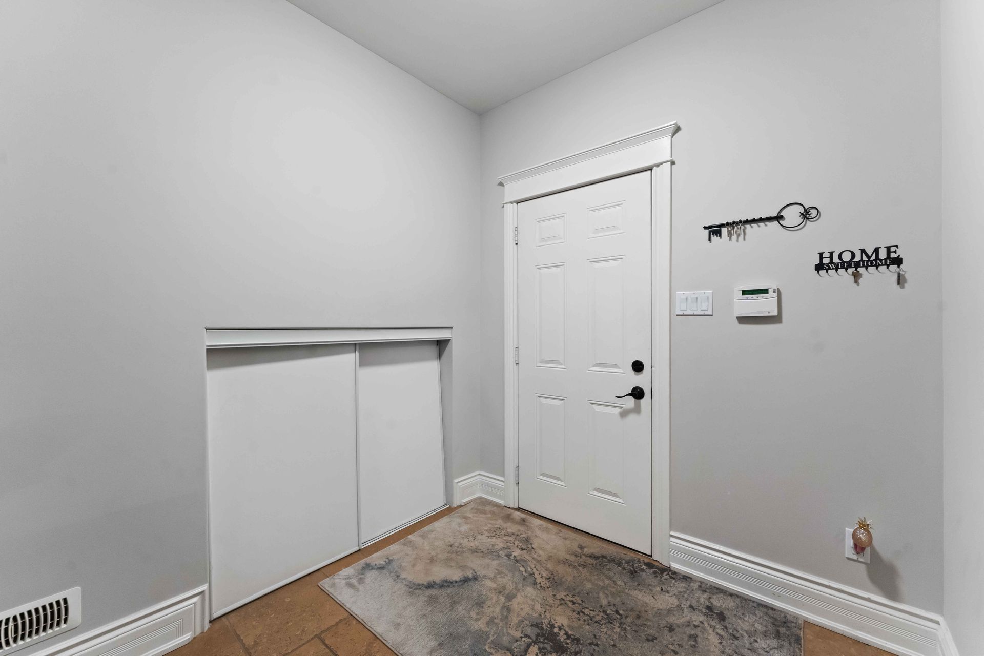 A corner of a room with a door and a rug.