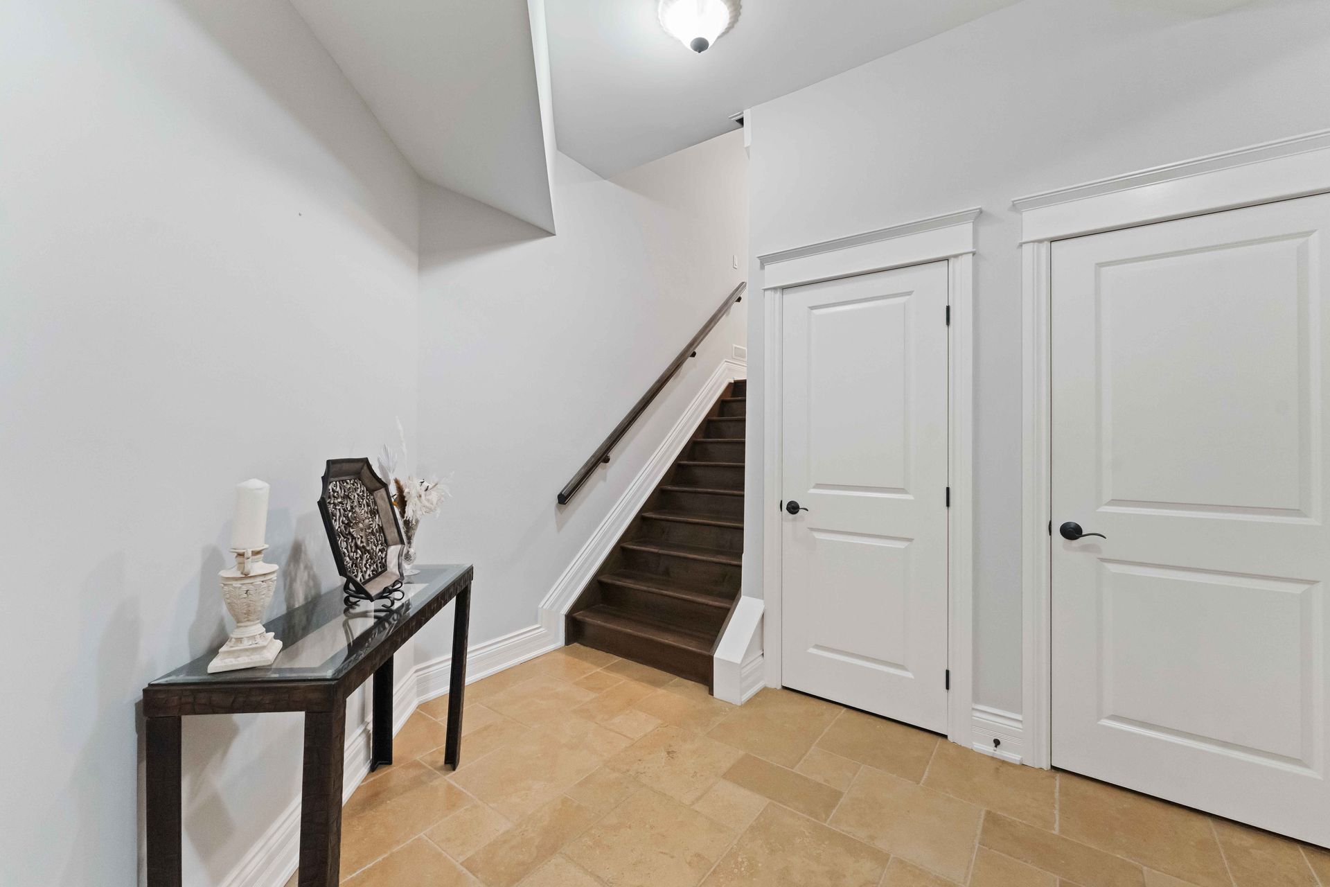A hallway with stairs and a table in the middle of it.