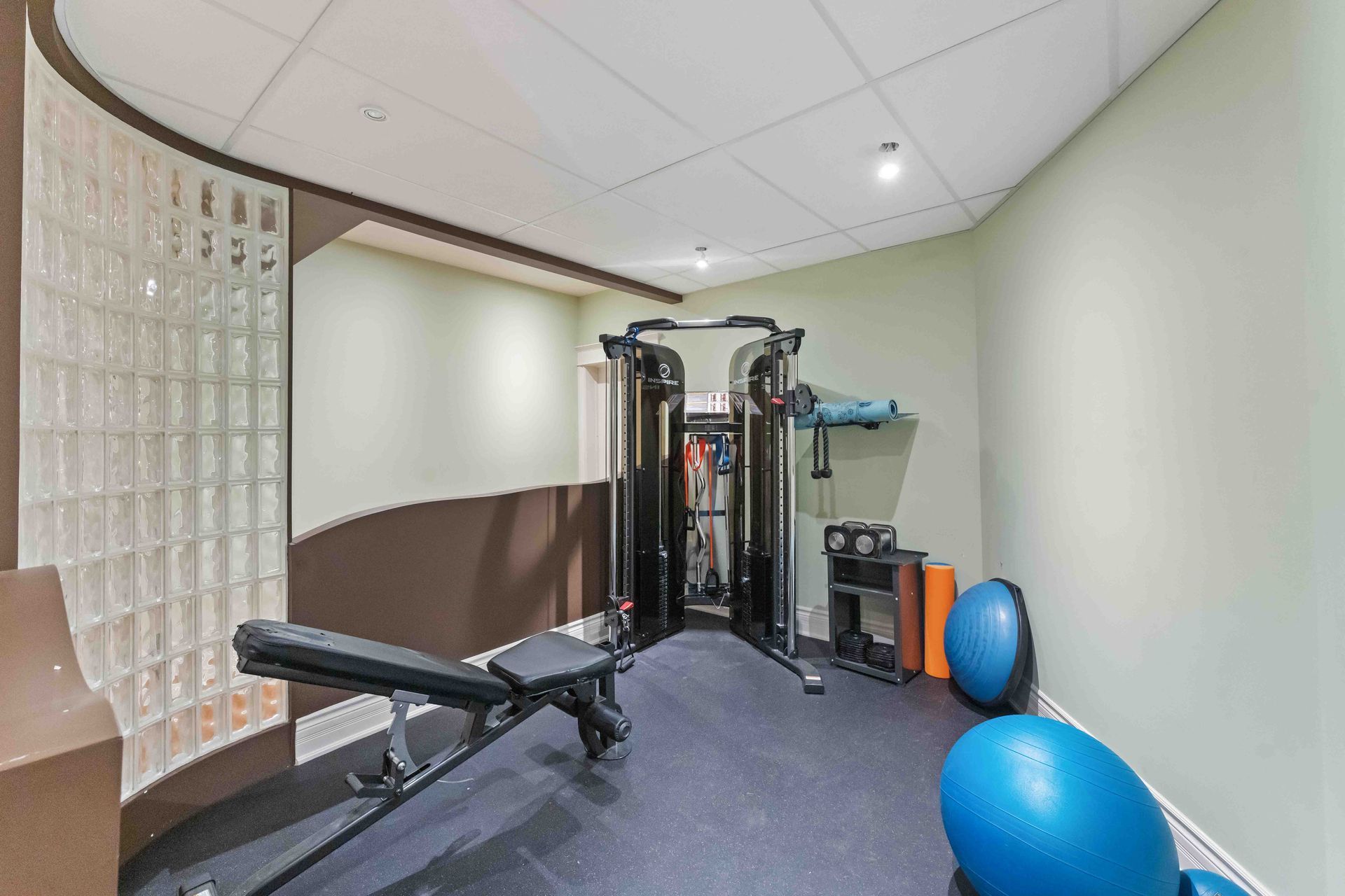 A gym with a bench , exercise ball , and other exercise equipment.