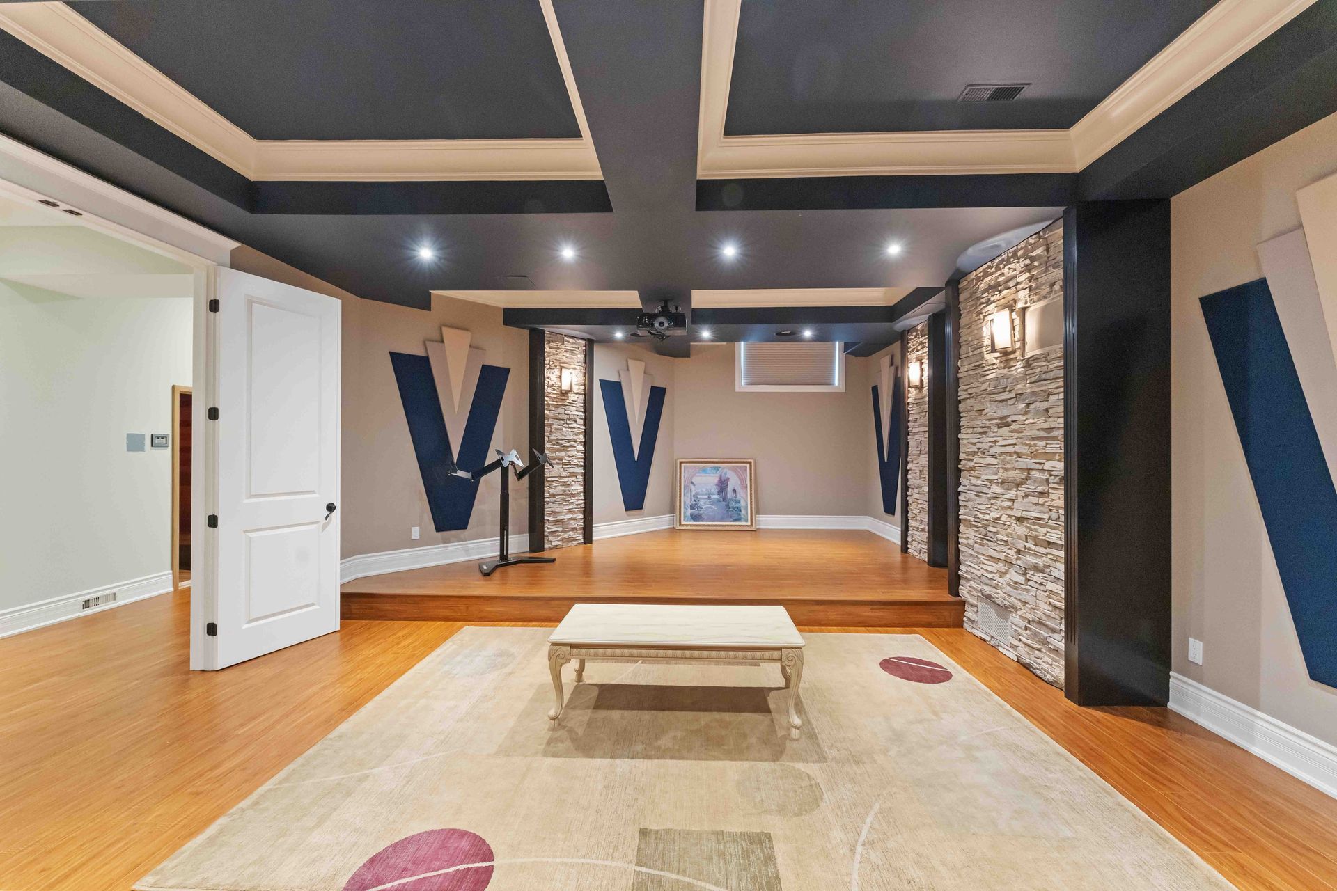 A living room with a rug and a ceiling that has the letter v on it