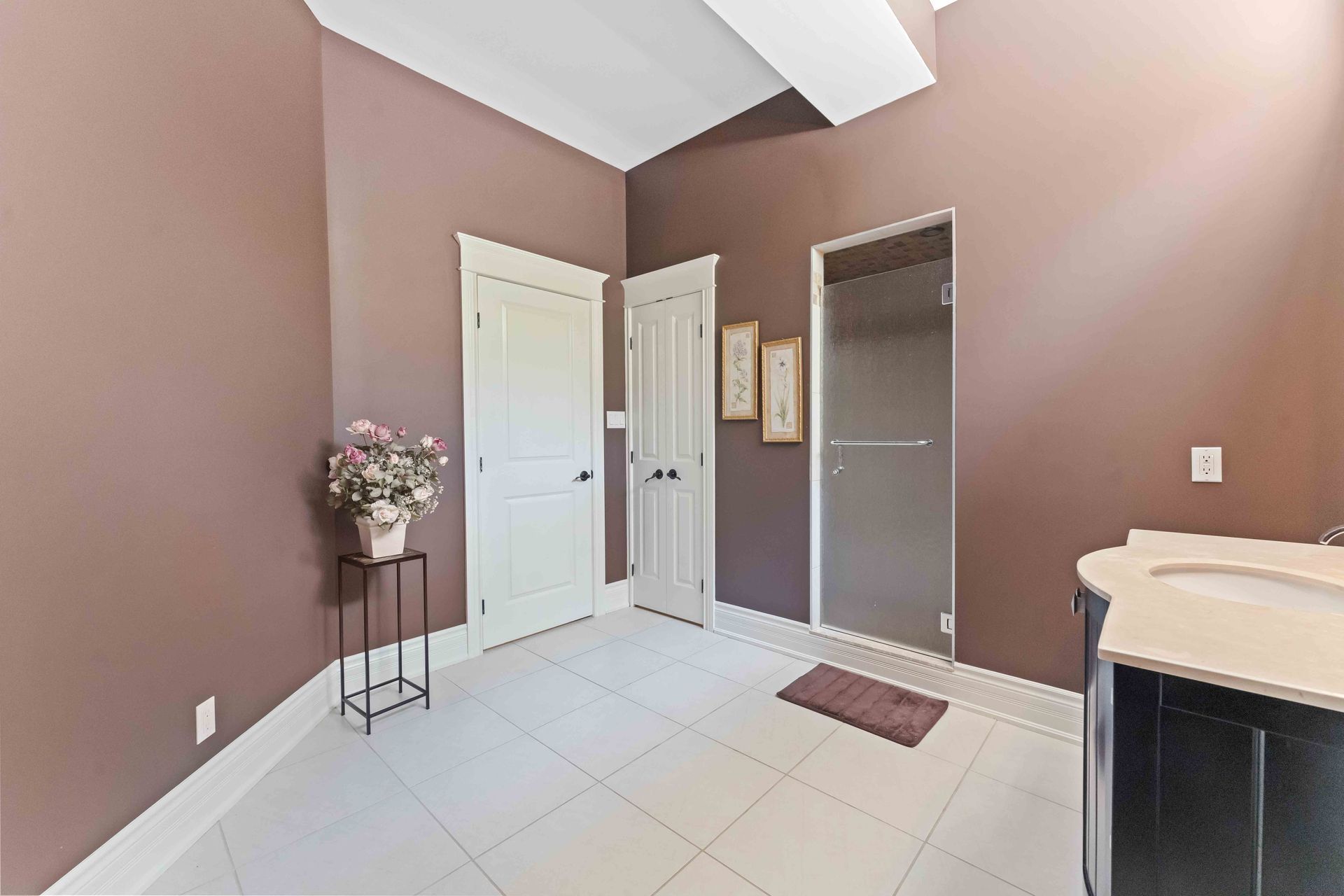 A bathroom with brown walls and white tile floors and a sink.