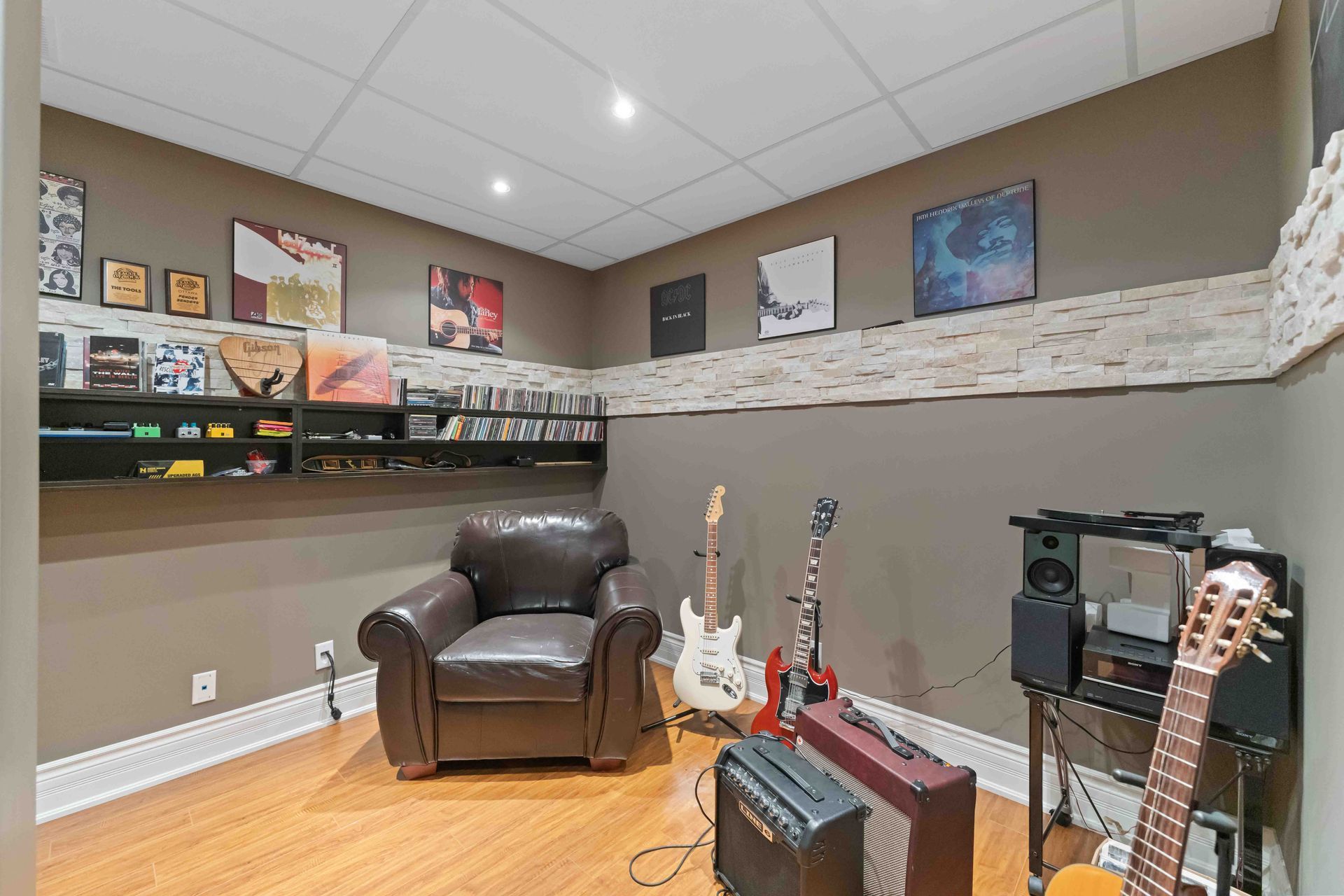 A living room with a chair , guitars , and amplifier.