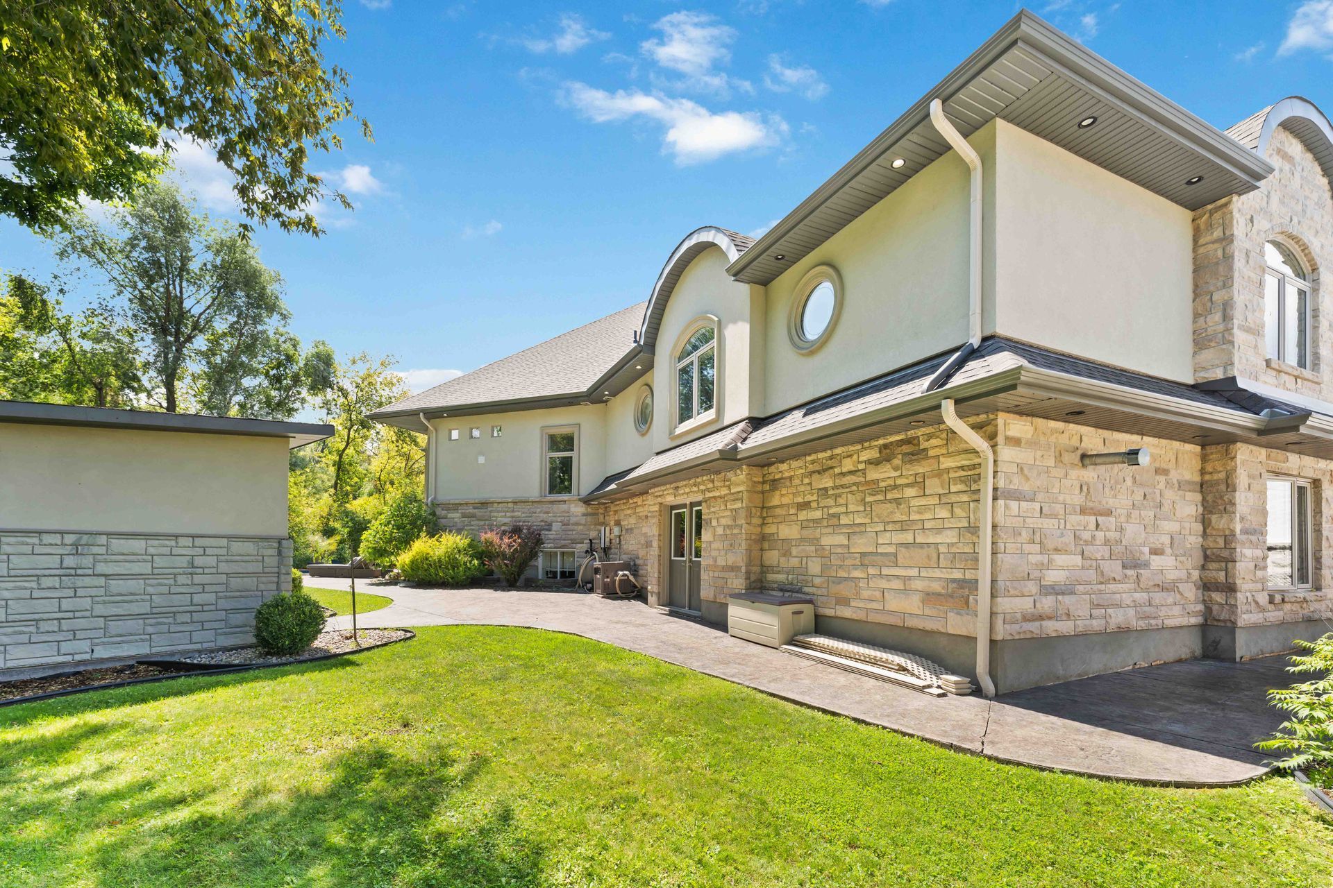 A large white house with a stone facade is sitting on top of a lush green lawn.