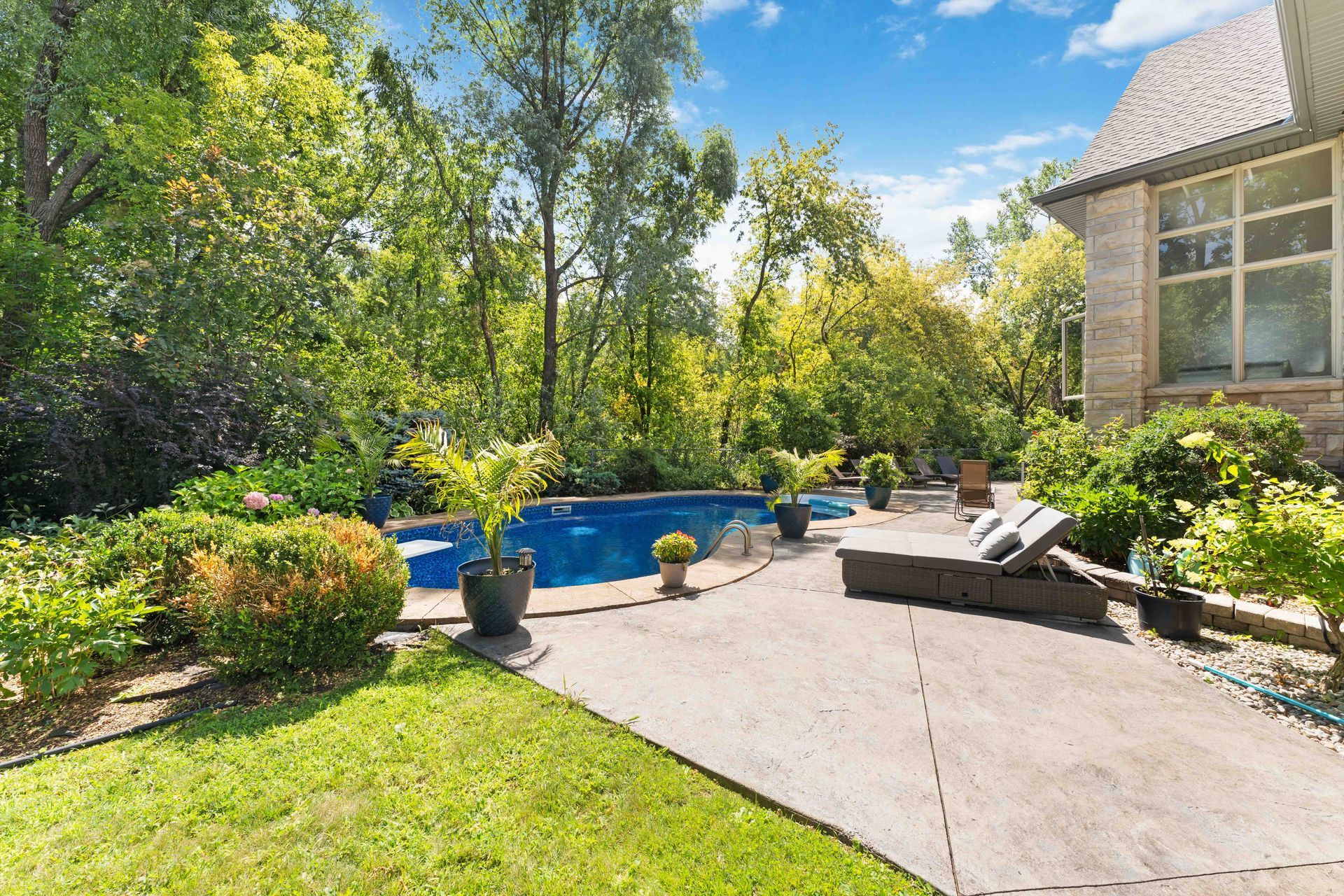 There is a large swimming pool in the backyard of a house.