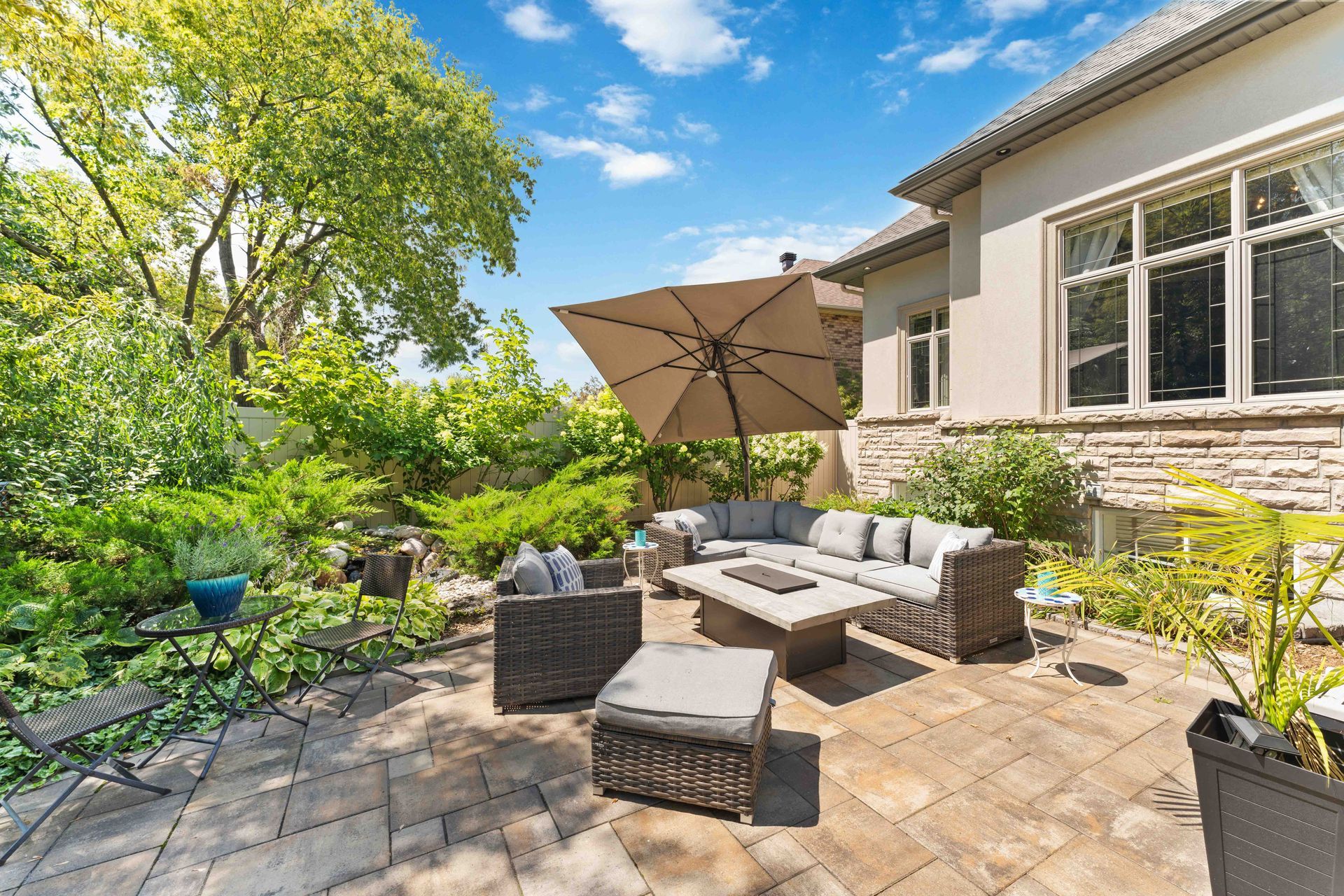A patio with furniture and an umbrella in front of a house.