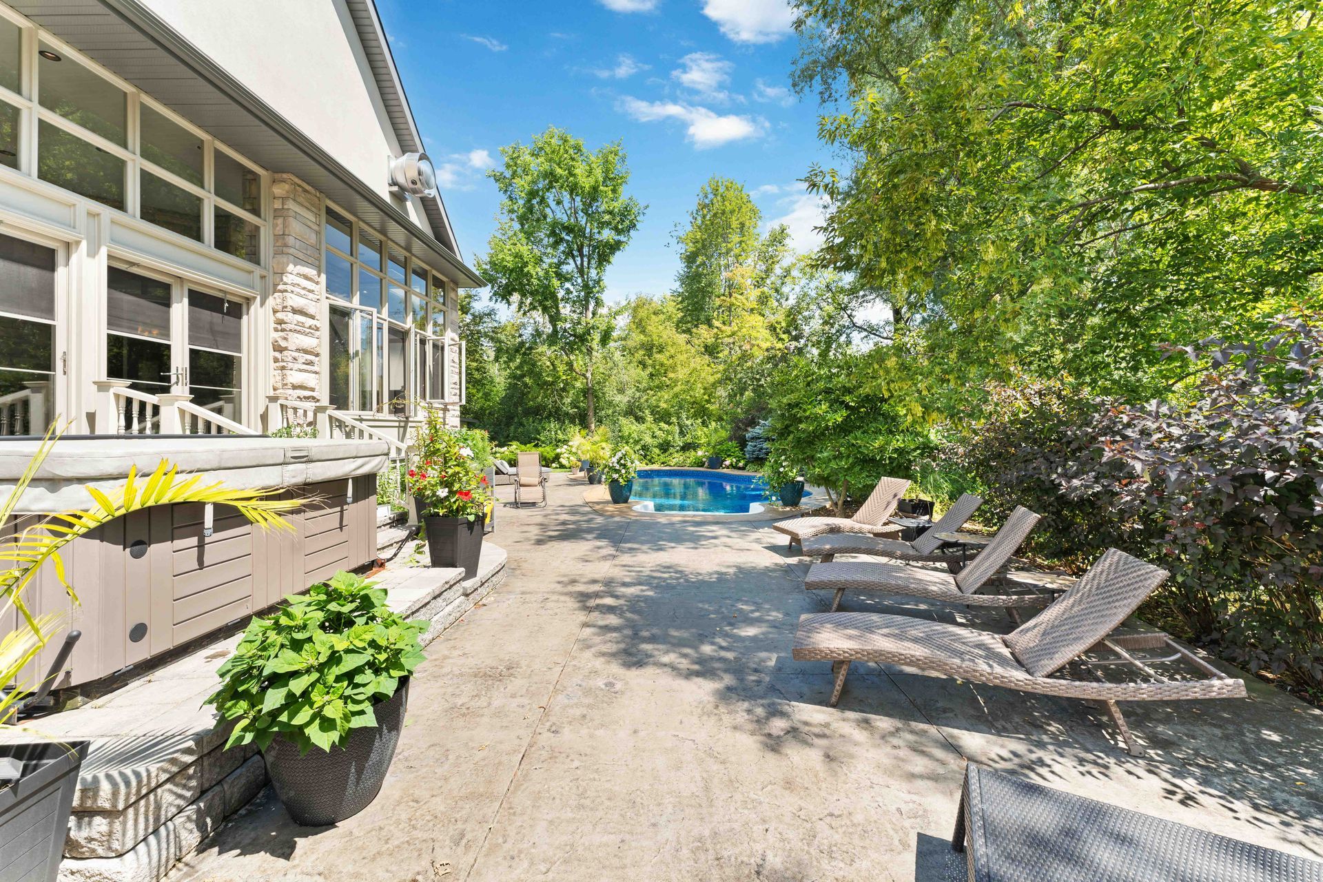 A patio with lawn chairs and a pool in the backyard of a house.