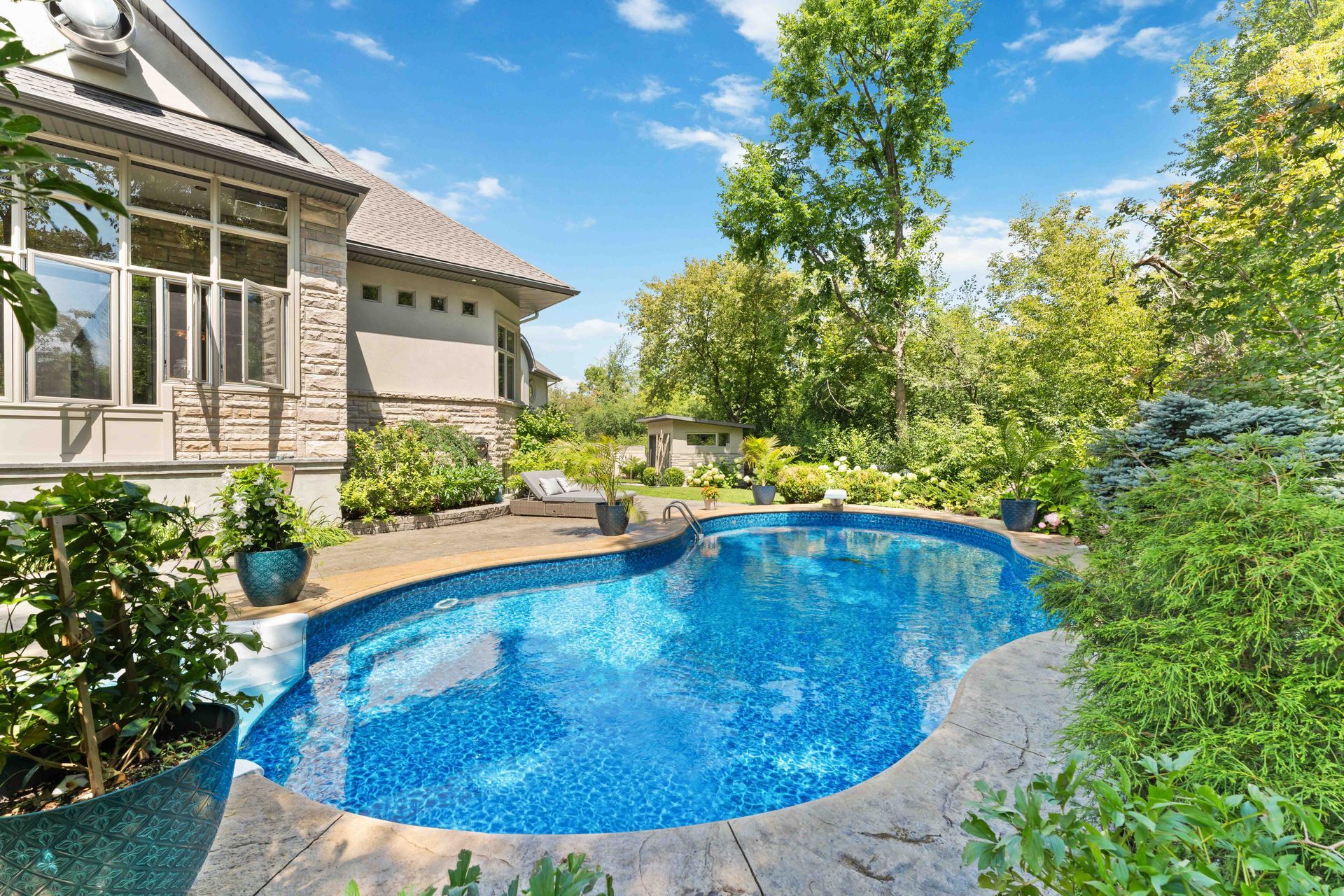 There is a large swimming pool in the backyard of a house.