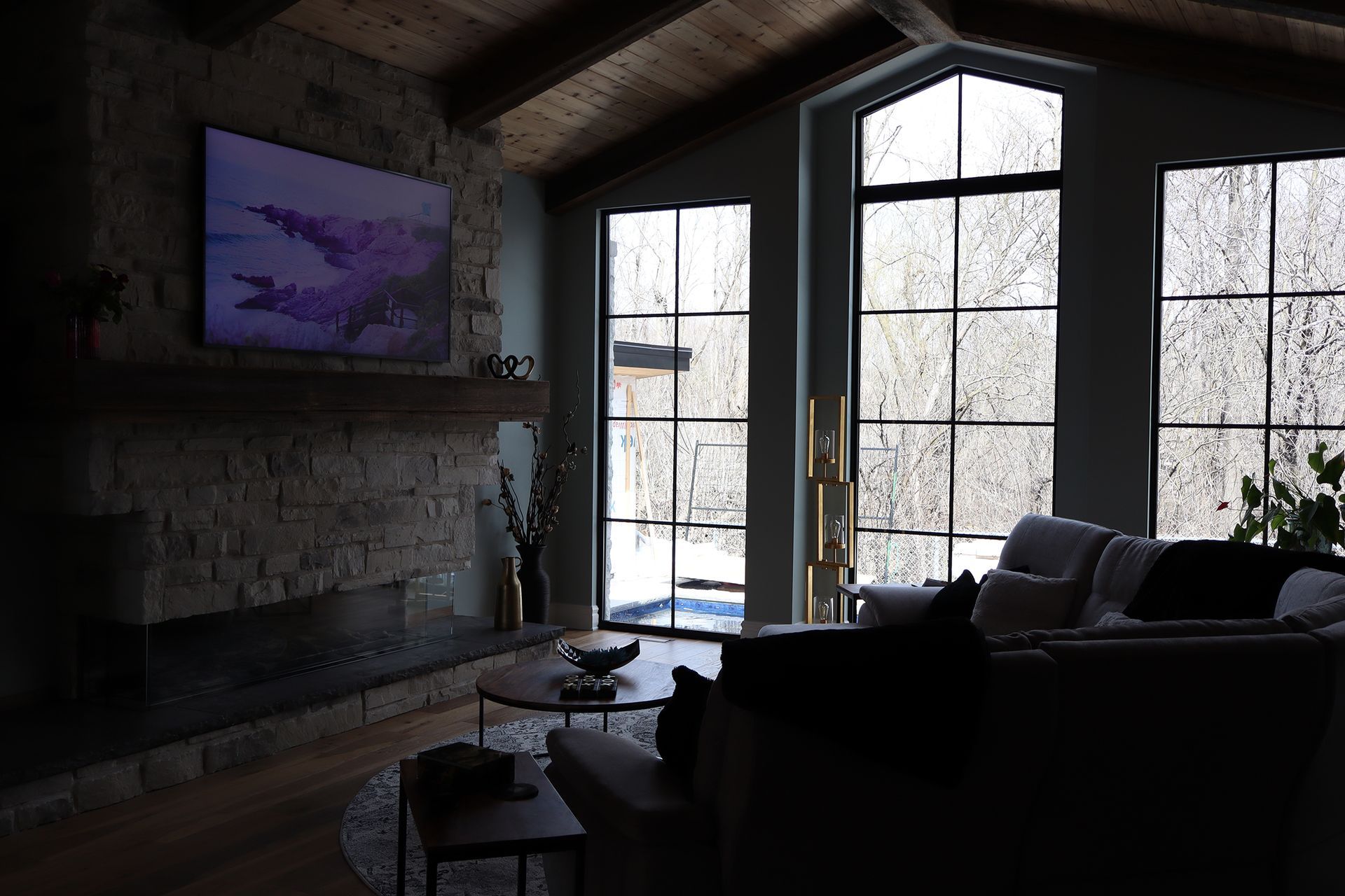 A living room with a couch , fireplace , television and large windows.