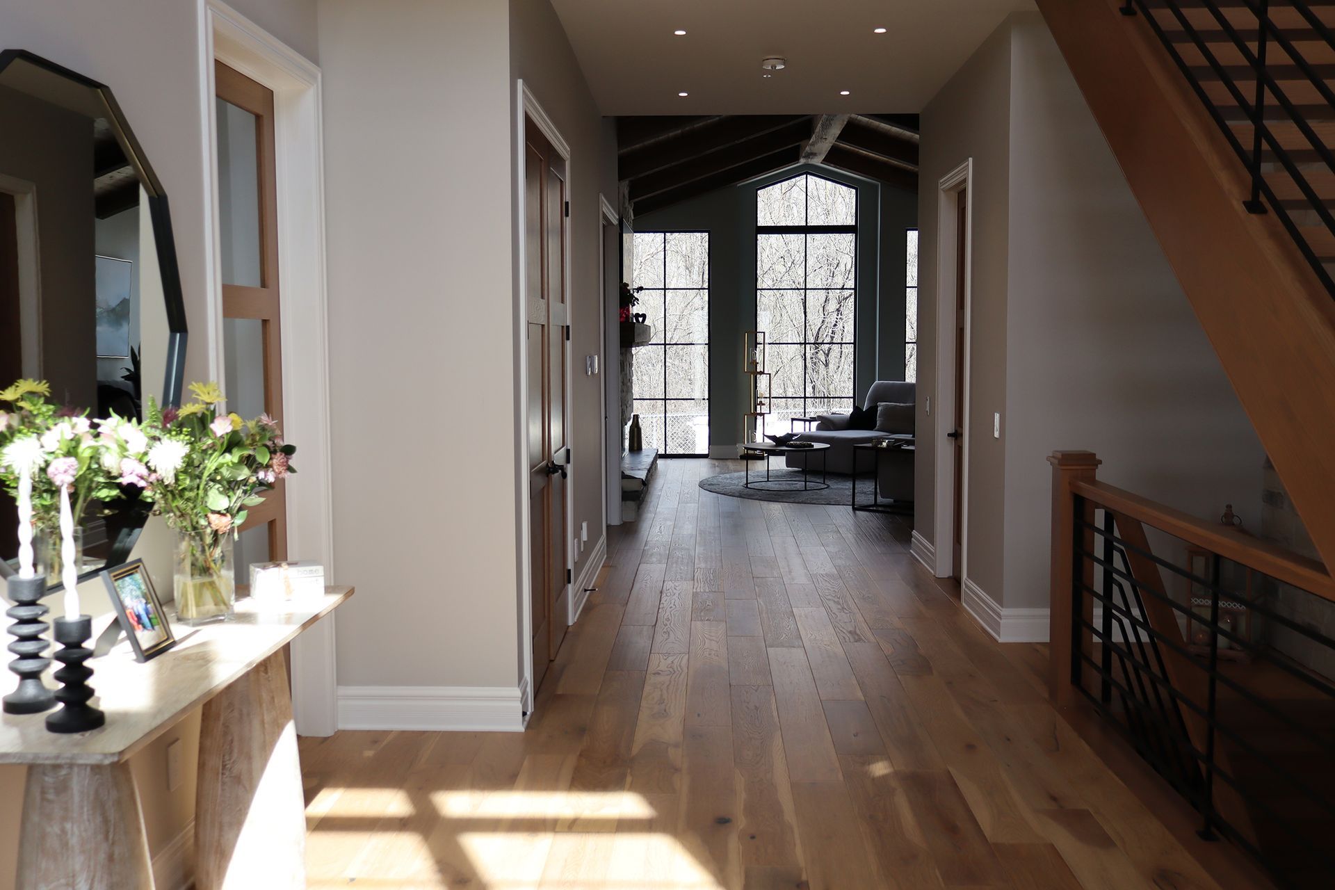 A hallway in a house with hardwood floors and a staircase.