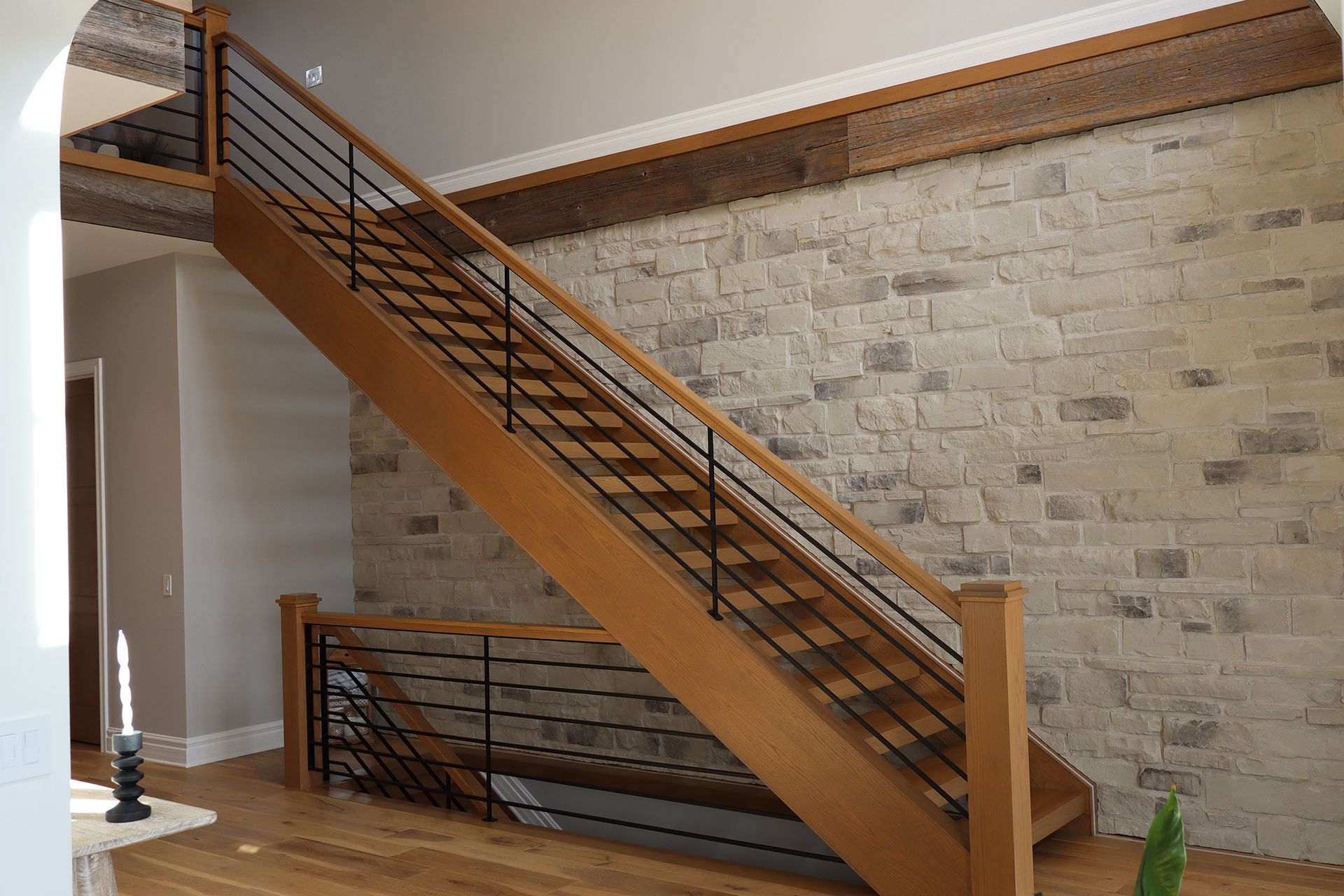 A wooden staircase with a metal railing in front of a brick wall.
