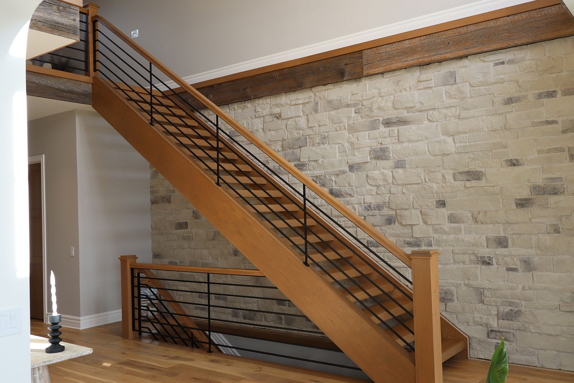 A wooden staircase with a metal railing in front of a brick wall.