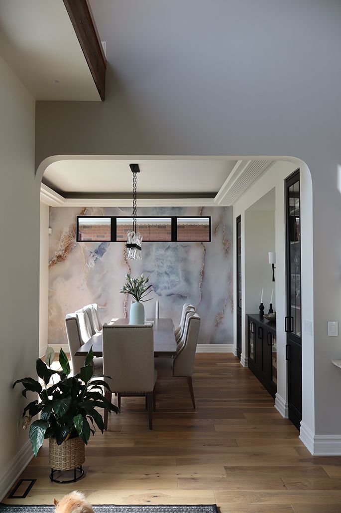 A dining room with a table and chairs and a potted plant.
