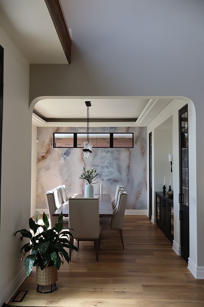 A dining room with a table and chairs and a potted plant.
