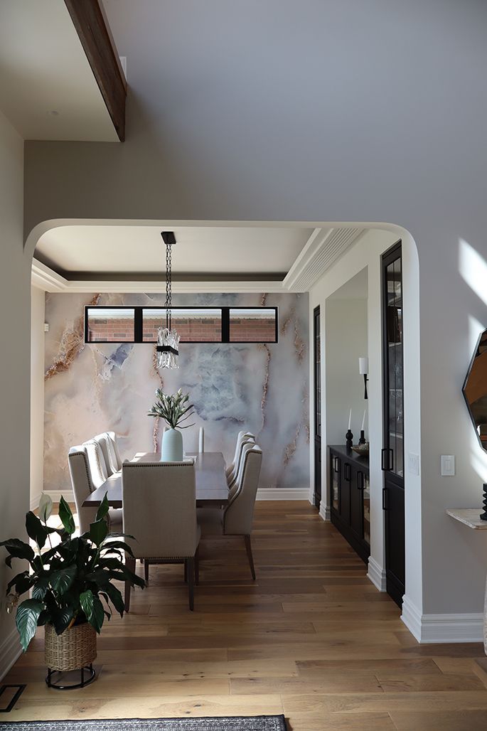 A dining room with a table and chairs and a potted plant.